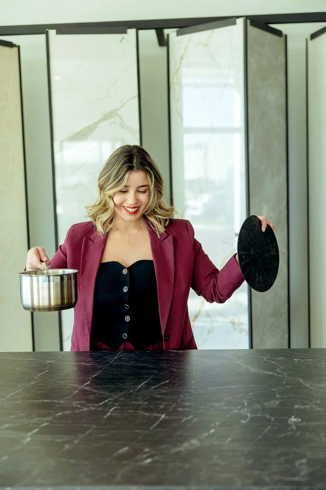 Mineral surface expert Lais Luz demonstrating an invisible induction cooking system integrated into a porcelain countertop.