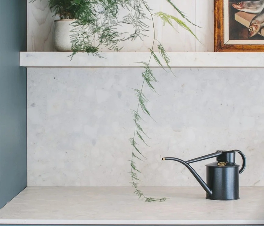 A luxury kitchen showcasing a seamless full-height porcelain slab backsplash with an integrated open floating shelf crafted from the same material with a thick mitered edge.