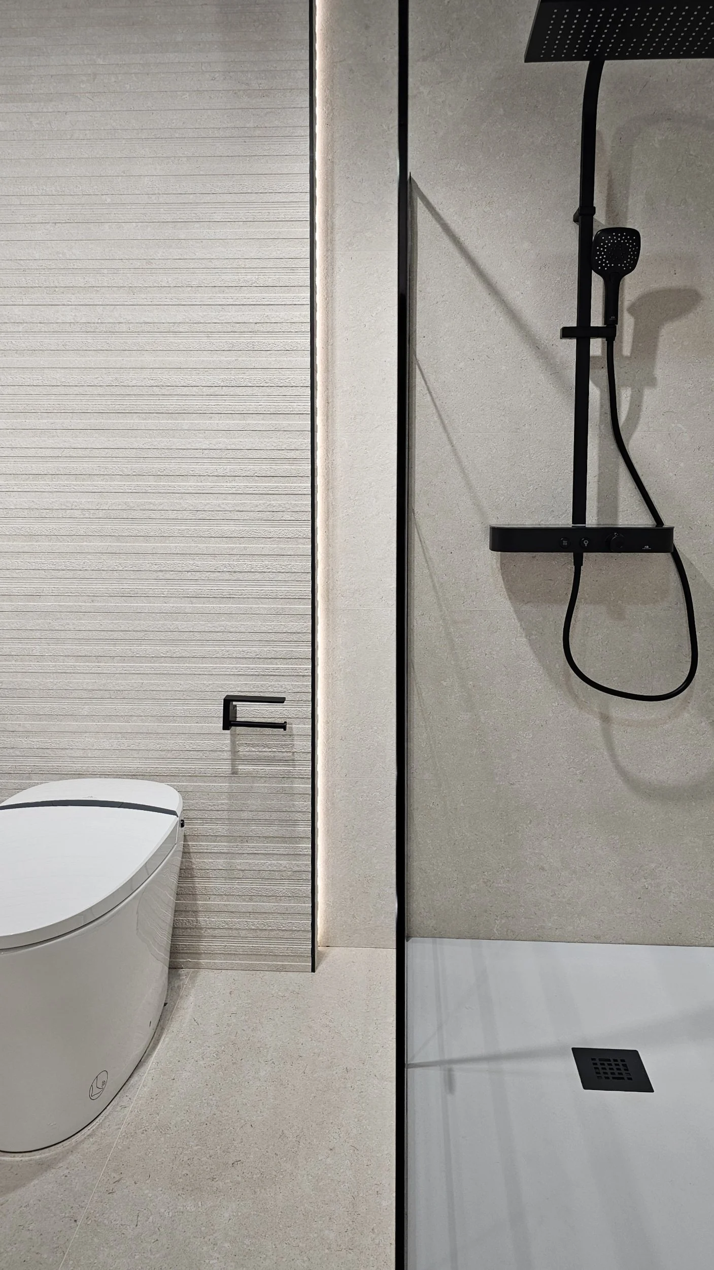 A luxury residential master bath featuring seamless full-height porcelain slab shower walls with continuous marble veining and zero grout lines.
