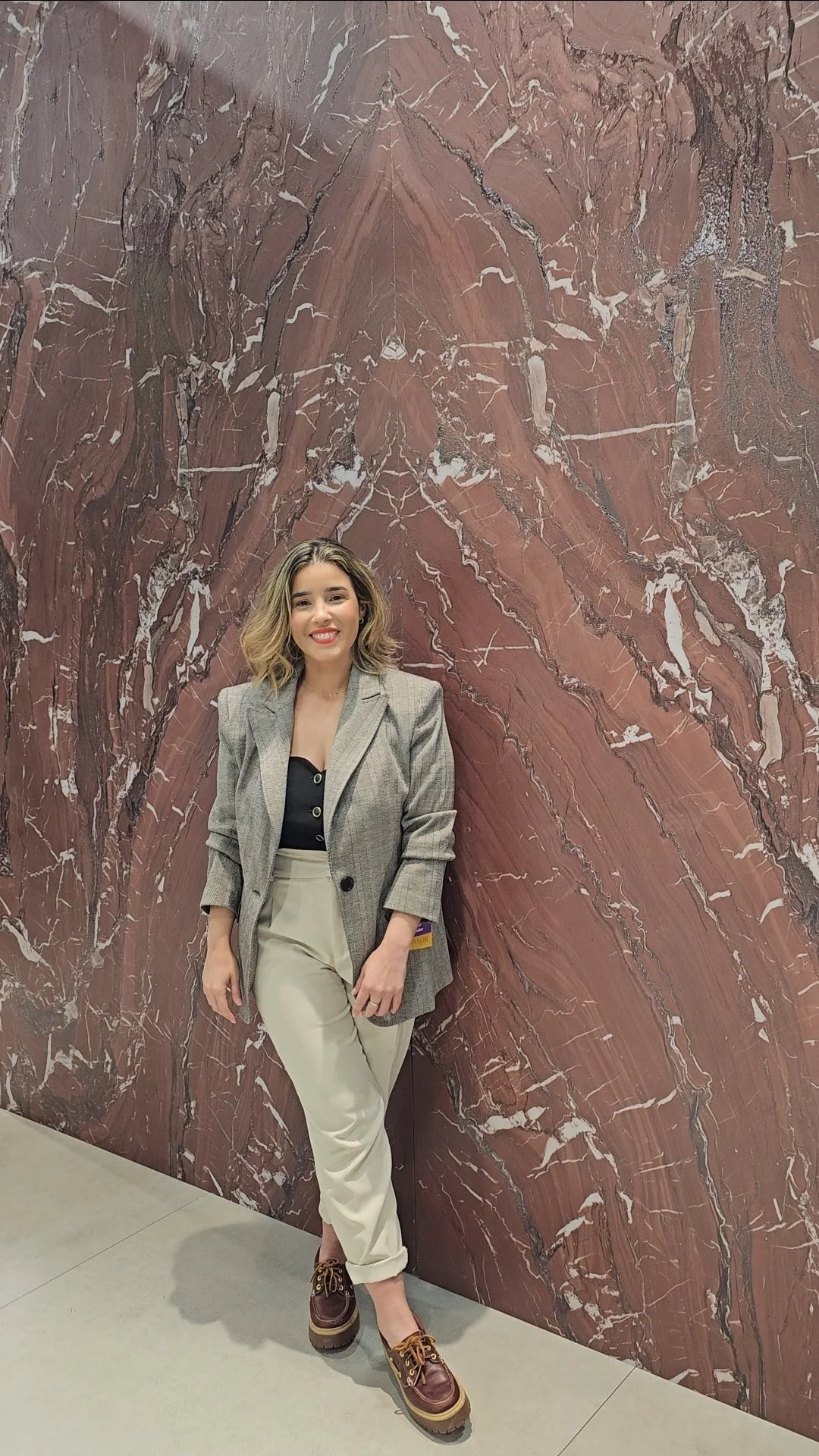 Lais Luz standing in front of a book-matched Rosso Cardinale porcelain slab by NG Kütahya at Coverings 2026.