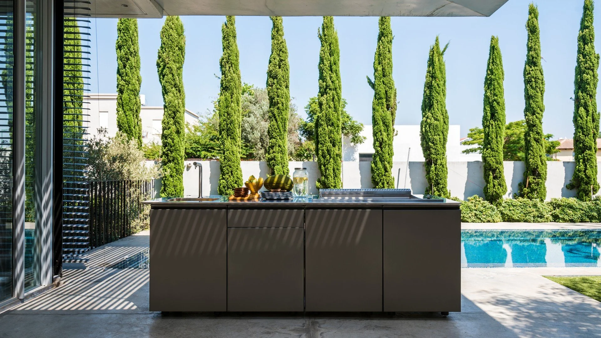 Premium white Capo Cuoco Unica luxury outdoor kitchen cabinets integrated with a custom porcelain slab countertop on a beachfront Siesta Key patio.