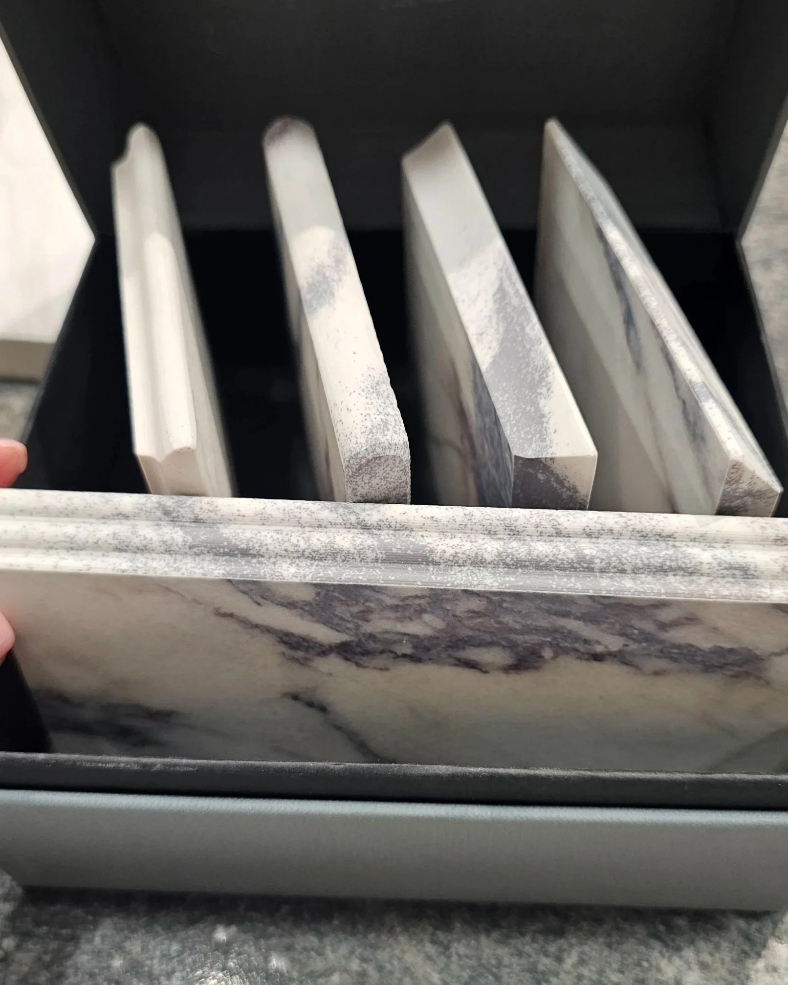 Lais Luz holding up a sample of SapienStone’s revolutionary 4D porcelain technology, showing the realistic veining structure on a solid 2cm counter edge profile.