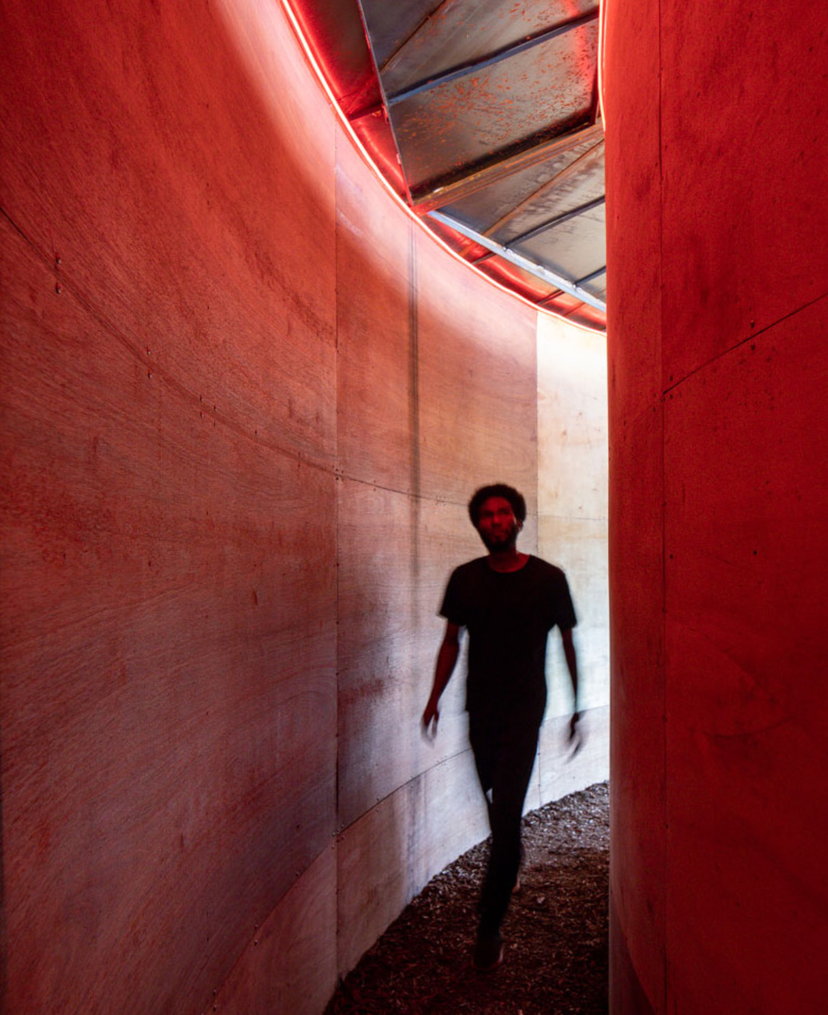Person walking through red light corridor of Helio Oiticica's PN15