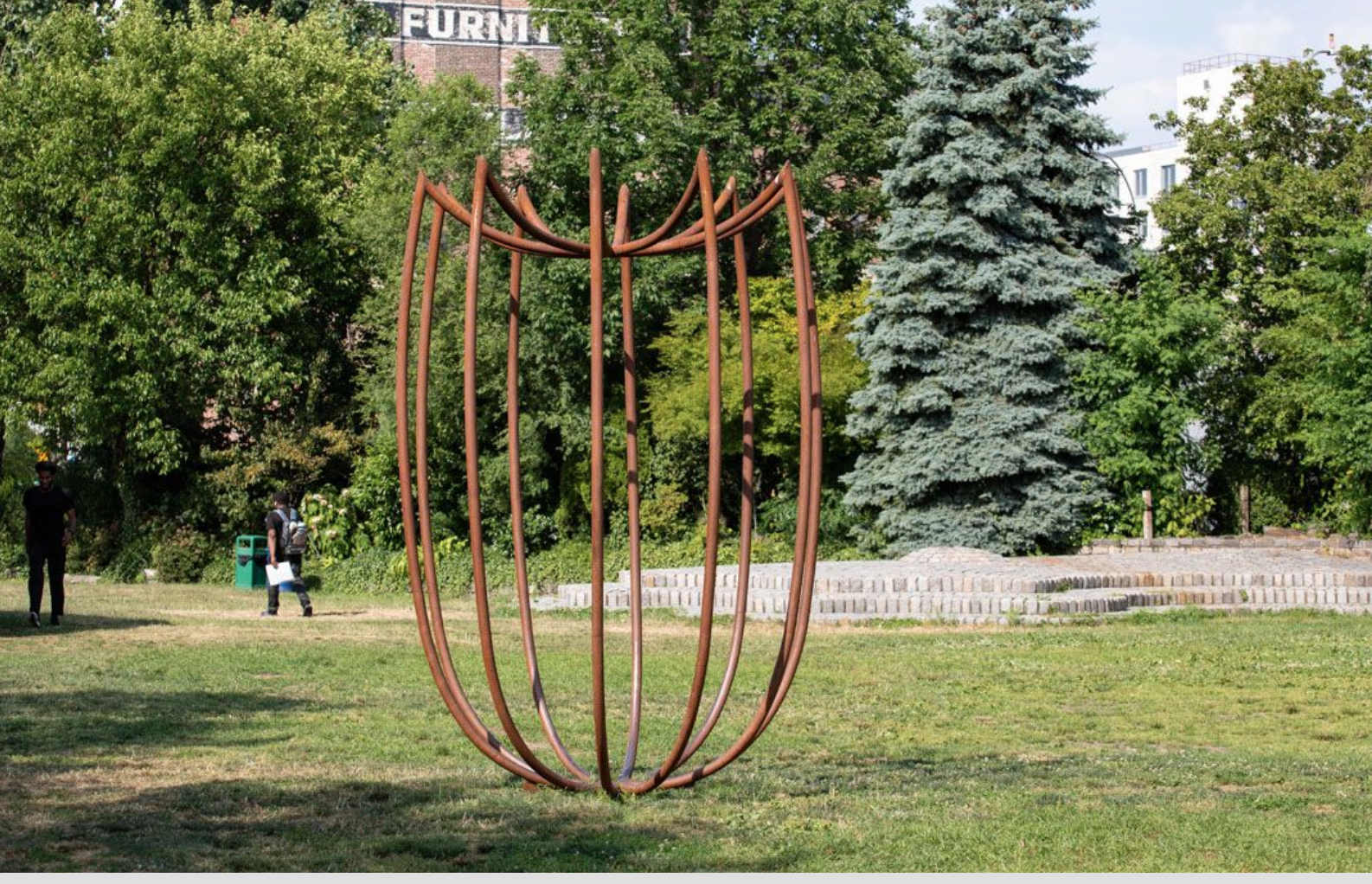 Maren Hassinger's outdoor sculpture oval vase rust color Vessel Seven in Steel Bodies in lush garden