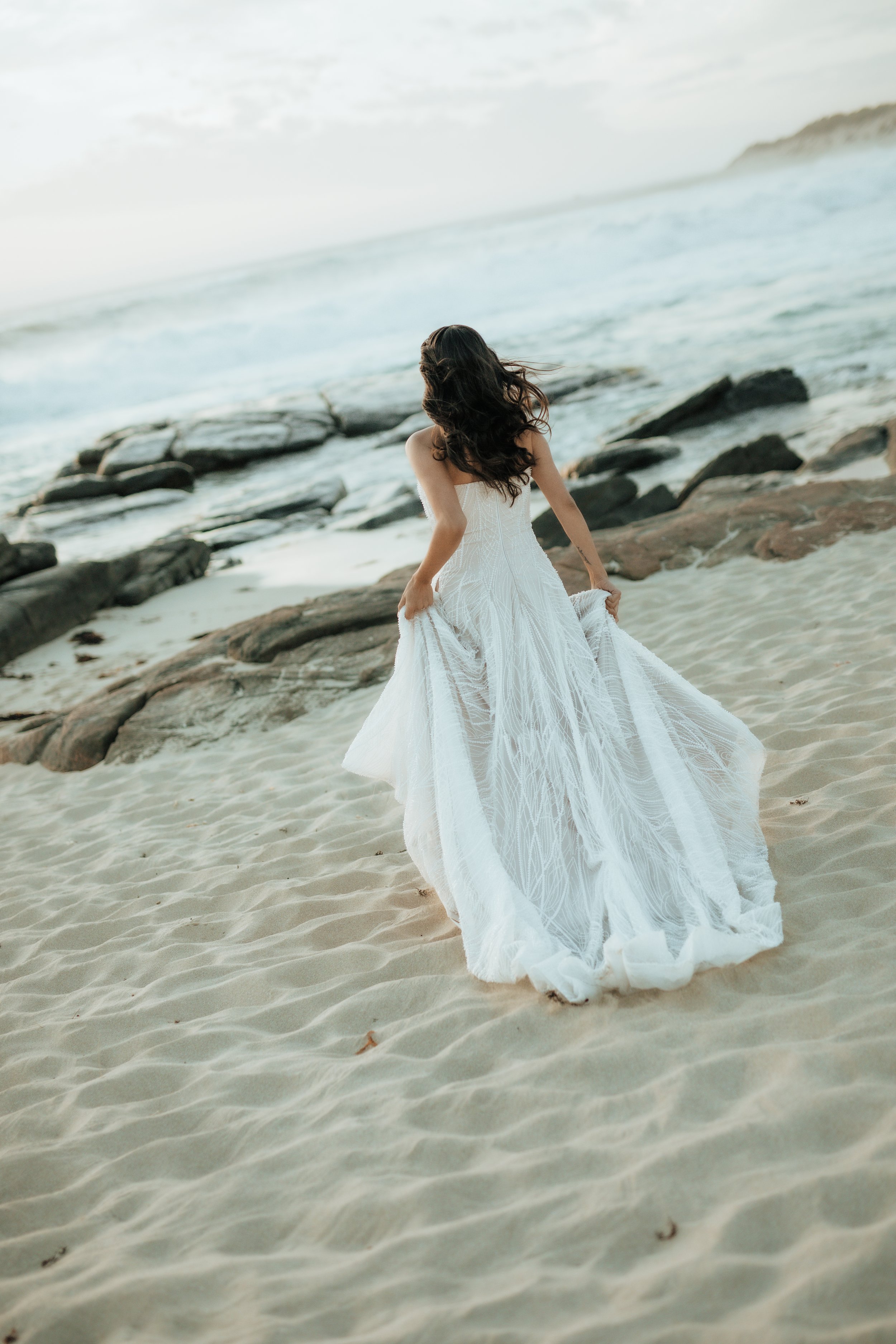 Bride running on beach with long dress
