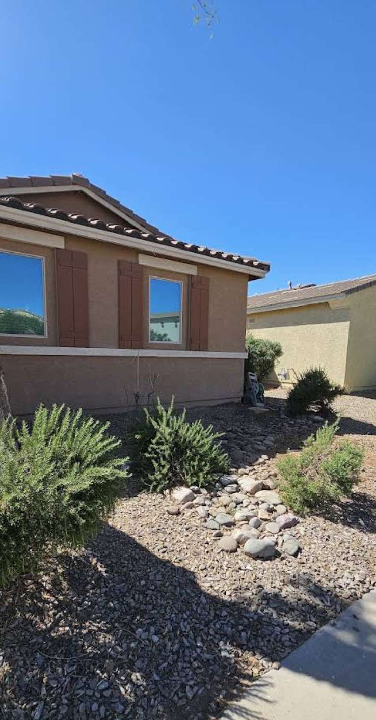Open desert planting area beside the home after tree removal and cleanup