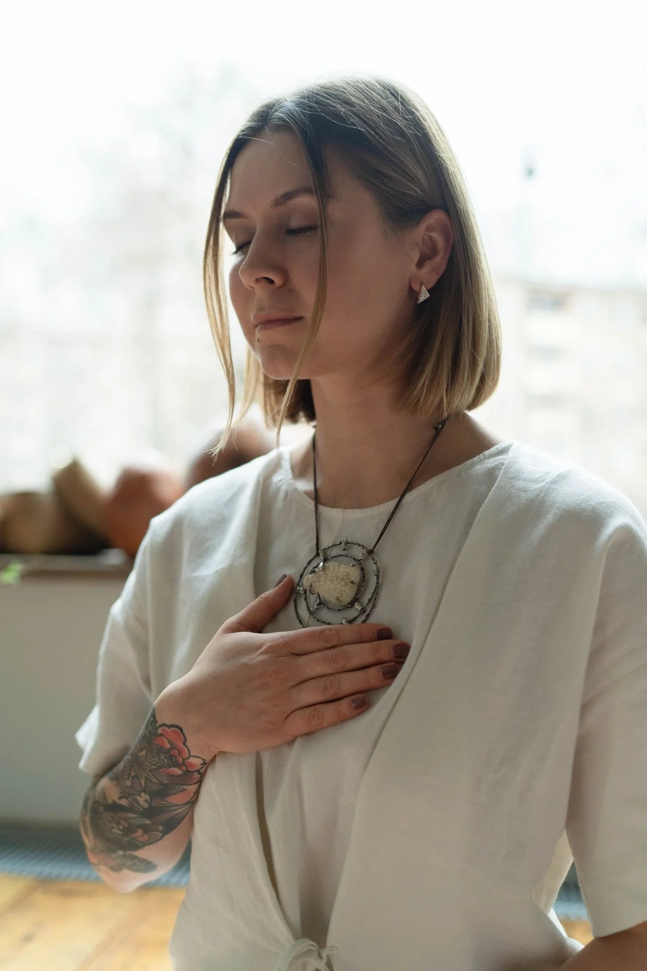 A mom with her eyes closed and one hand on her chest, taking a slow breath.