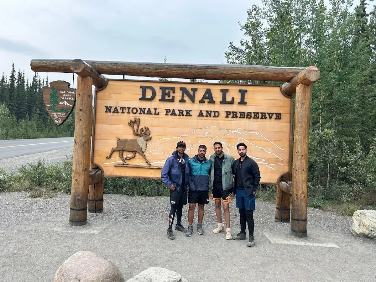 Group travelers standing in front of the Denali National Park entry sign