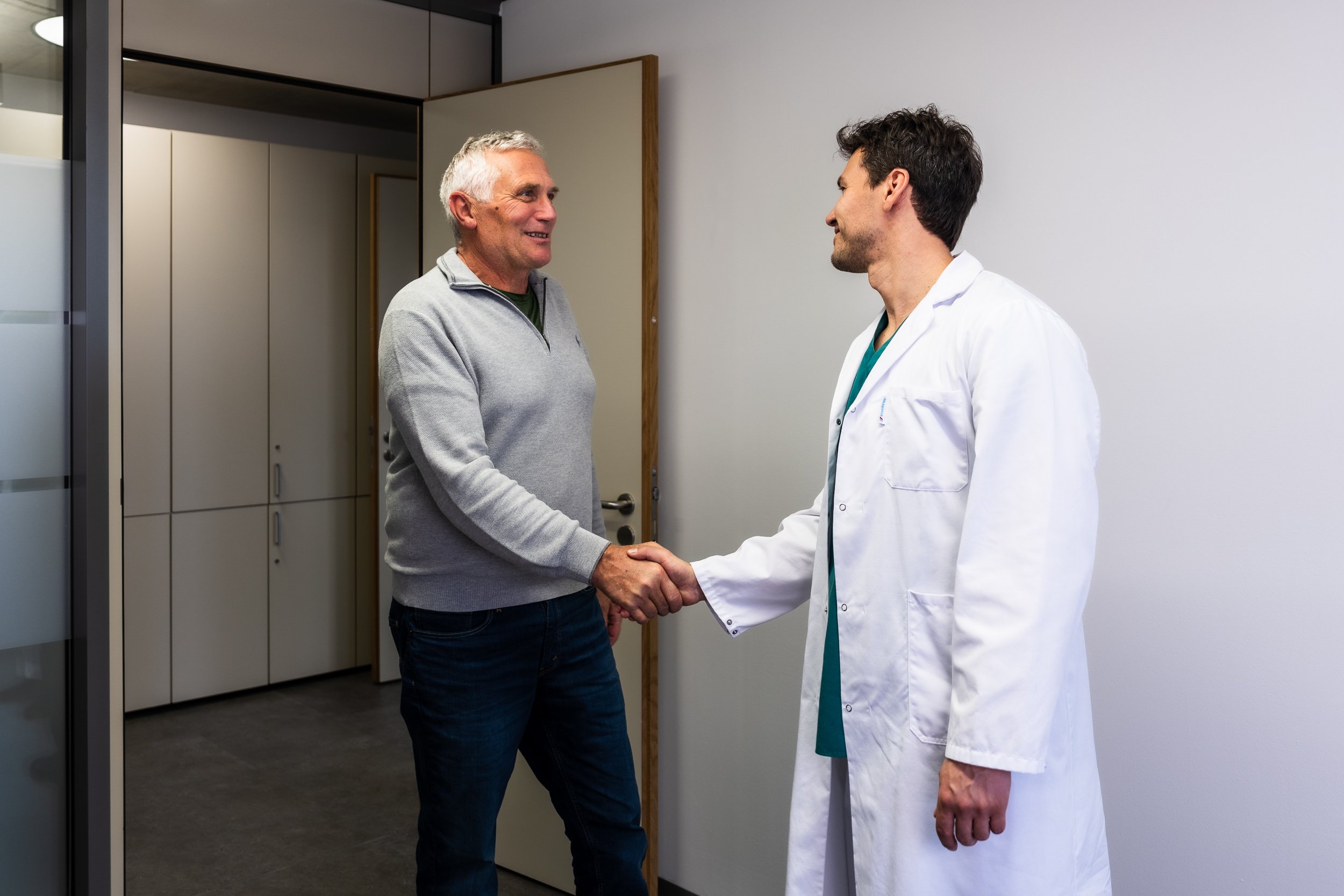 Dr.med. René Fischlechner, Spezialist für Hals-, Nasen- und Ohrenerkrankungen begrüßt einen Patienten in seiner Ordination in Hall in Tirol.