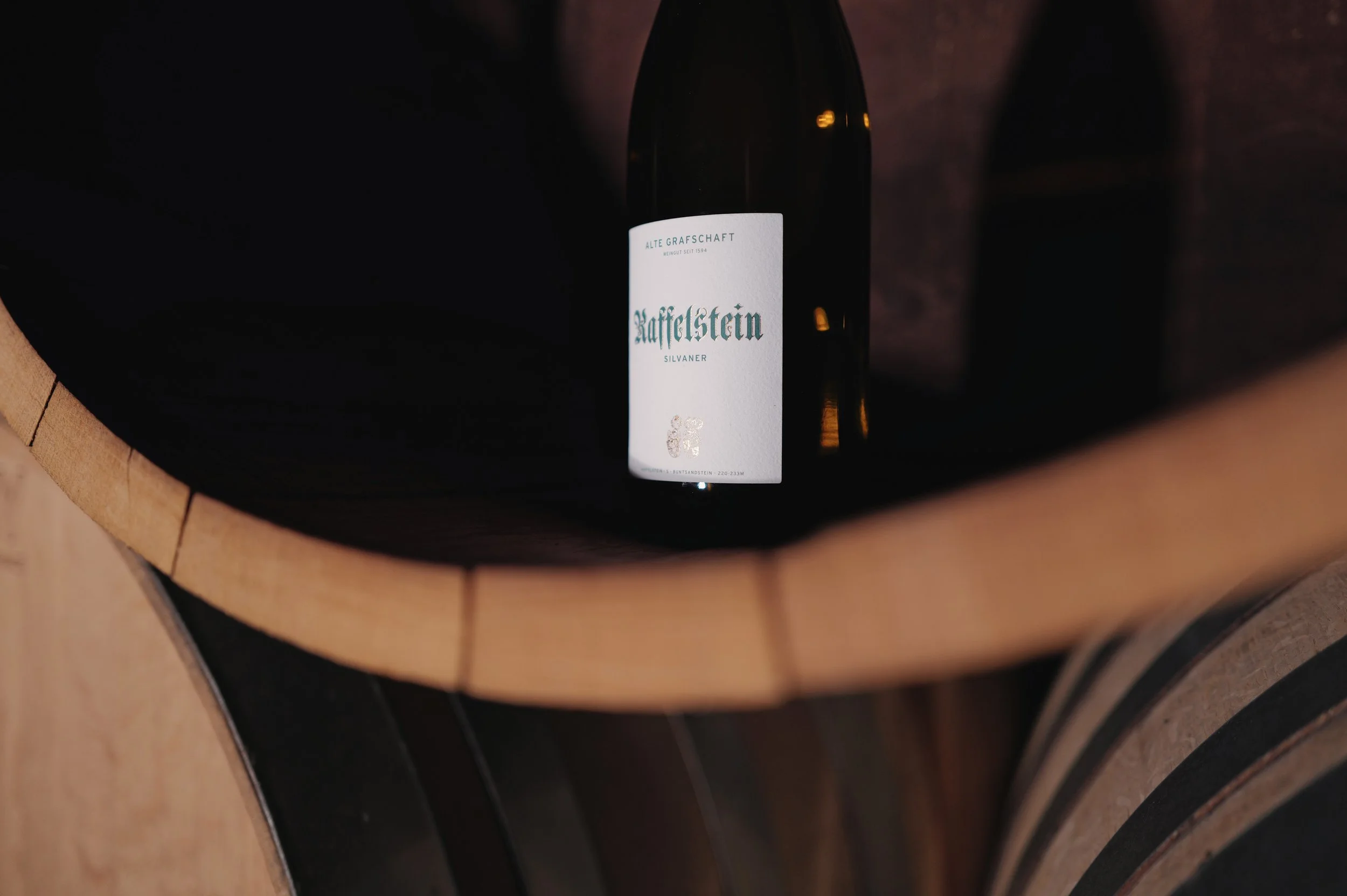 Eine Weinflasche in einem Weinkeller, zwischen Weinfässern