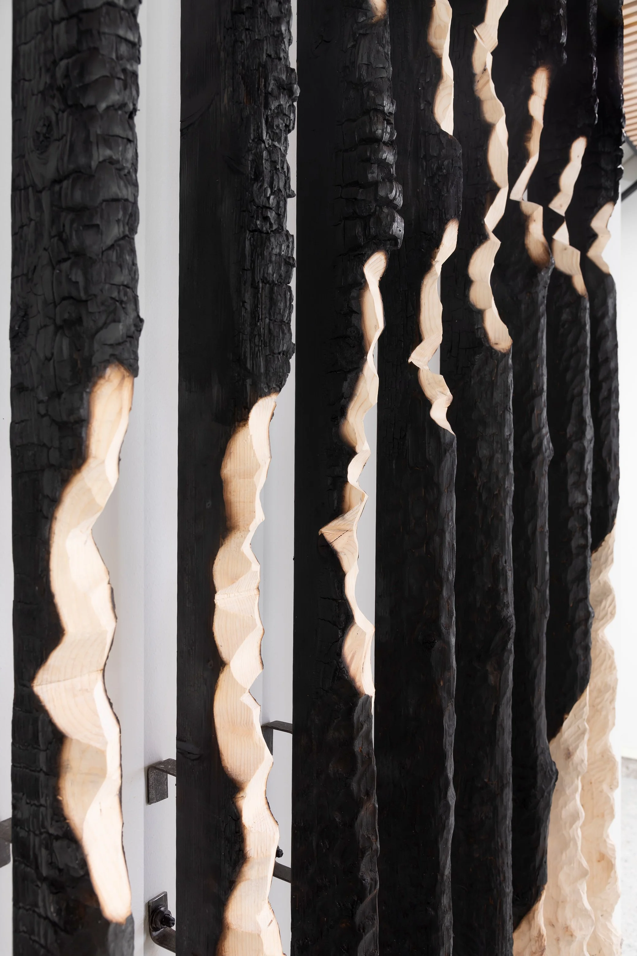 Close-up of vertical wooden panels with textured black and natural wood finishes.