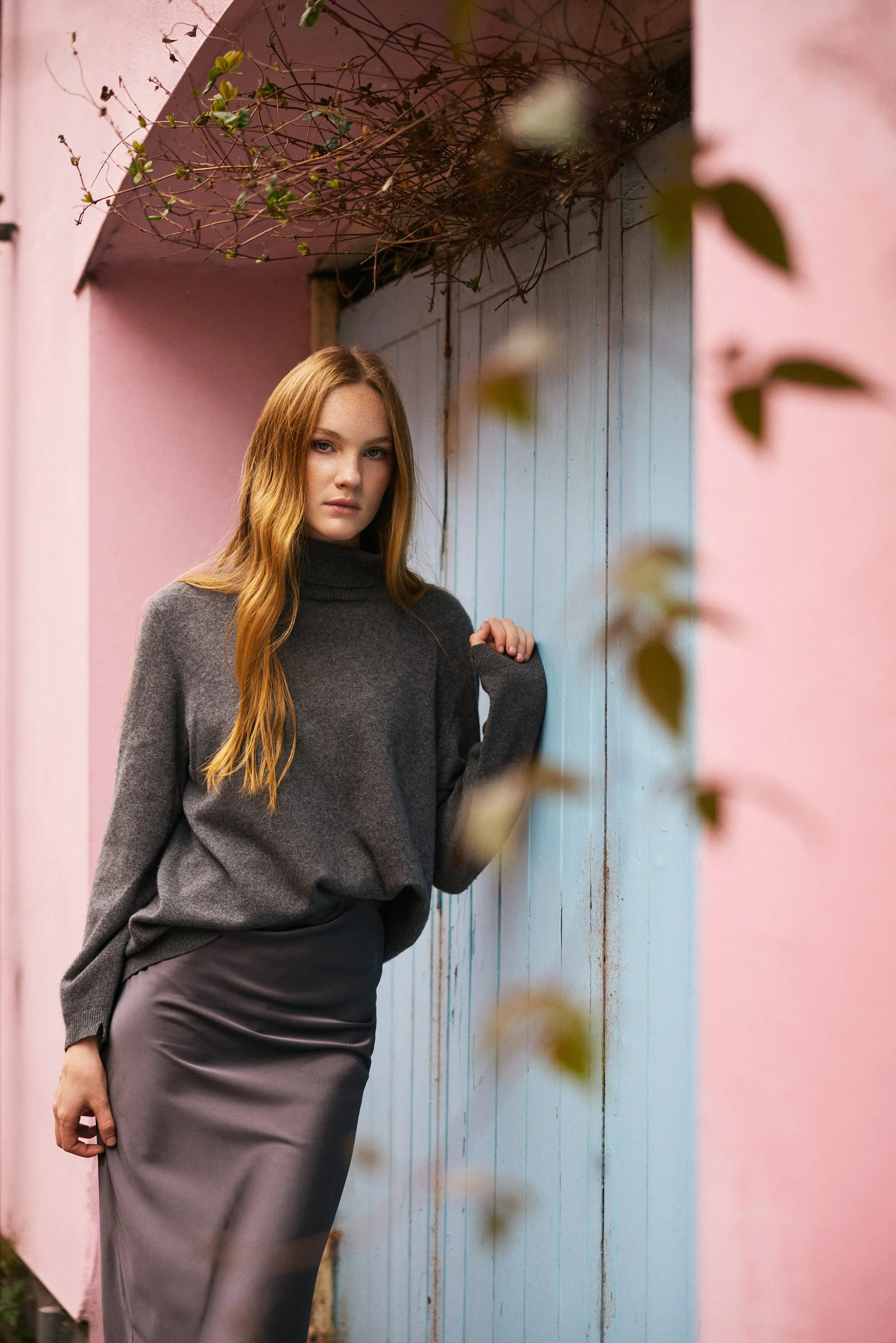 redhead model leans against blue door in pink wall.jpg