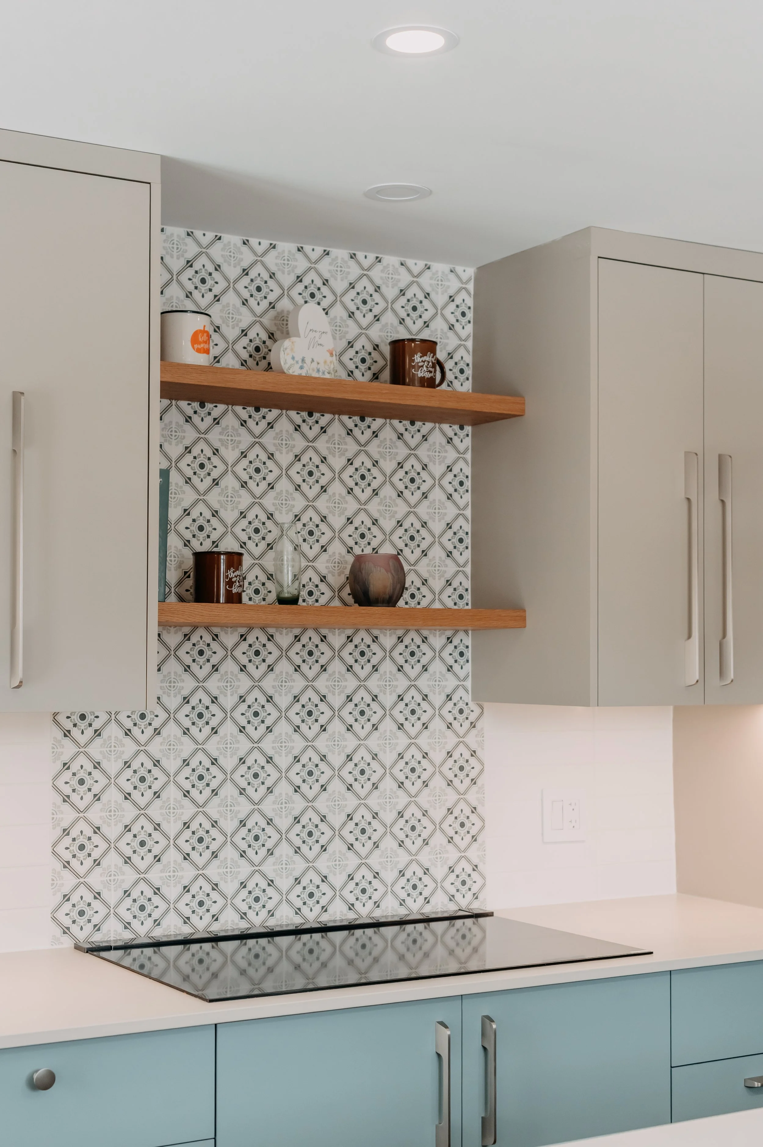 Open wood shelving and a patterned tile backsplash add texture next to the kitchen's signature blue tone.