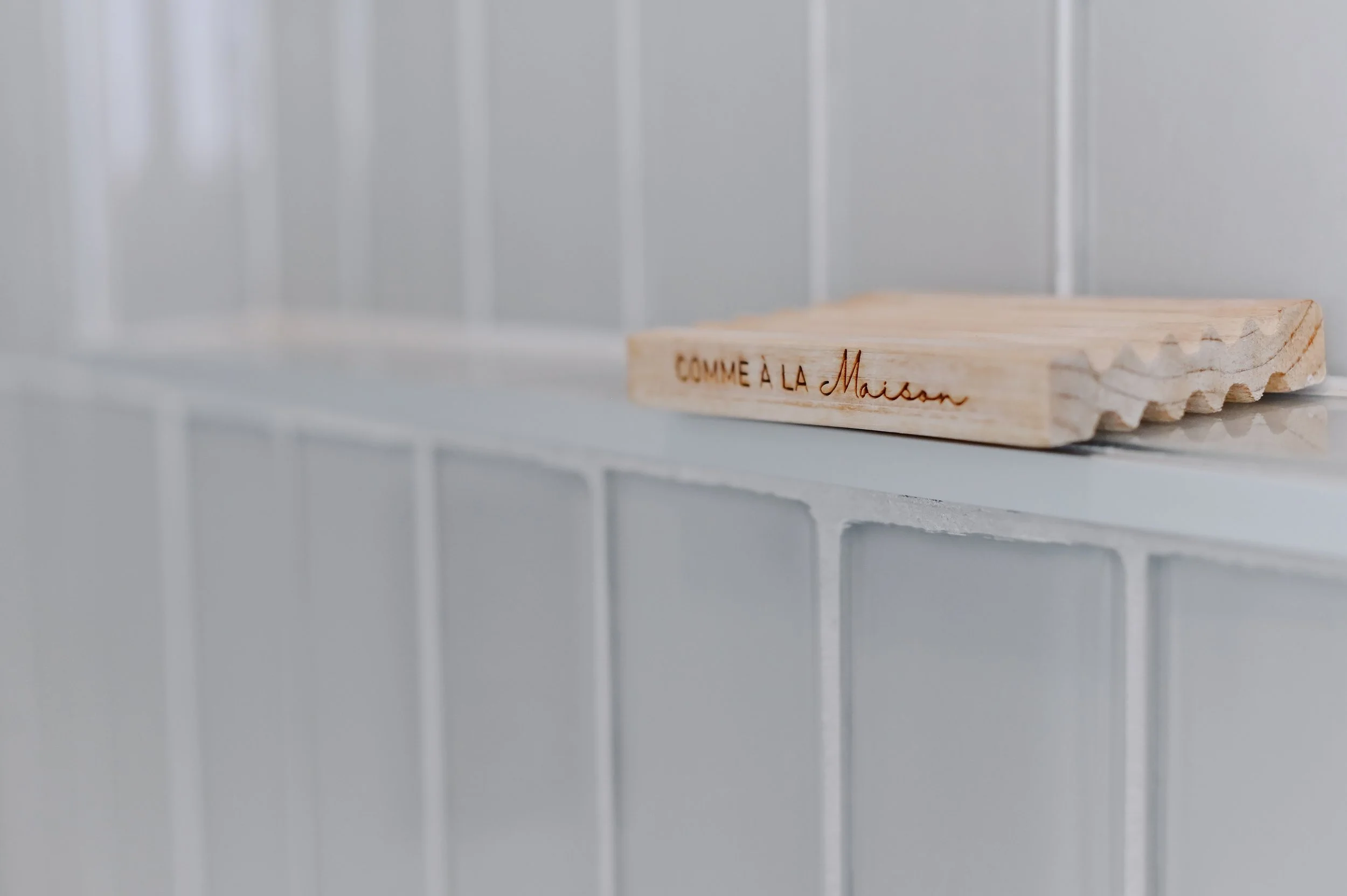 Wood soap dish with engraved lettering on glossy tiled wall, New York style ensuite