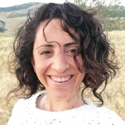 Picture of professional translator, Najat Keaik, standing in front of a golden field