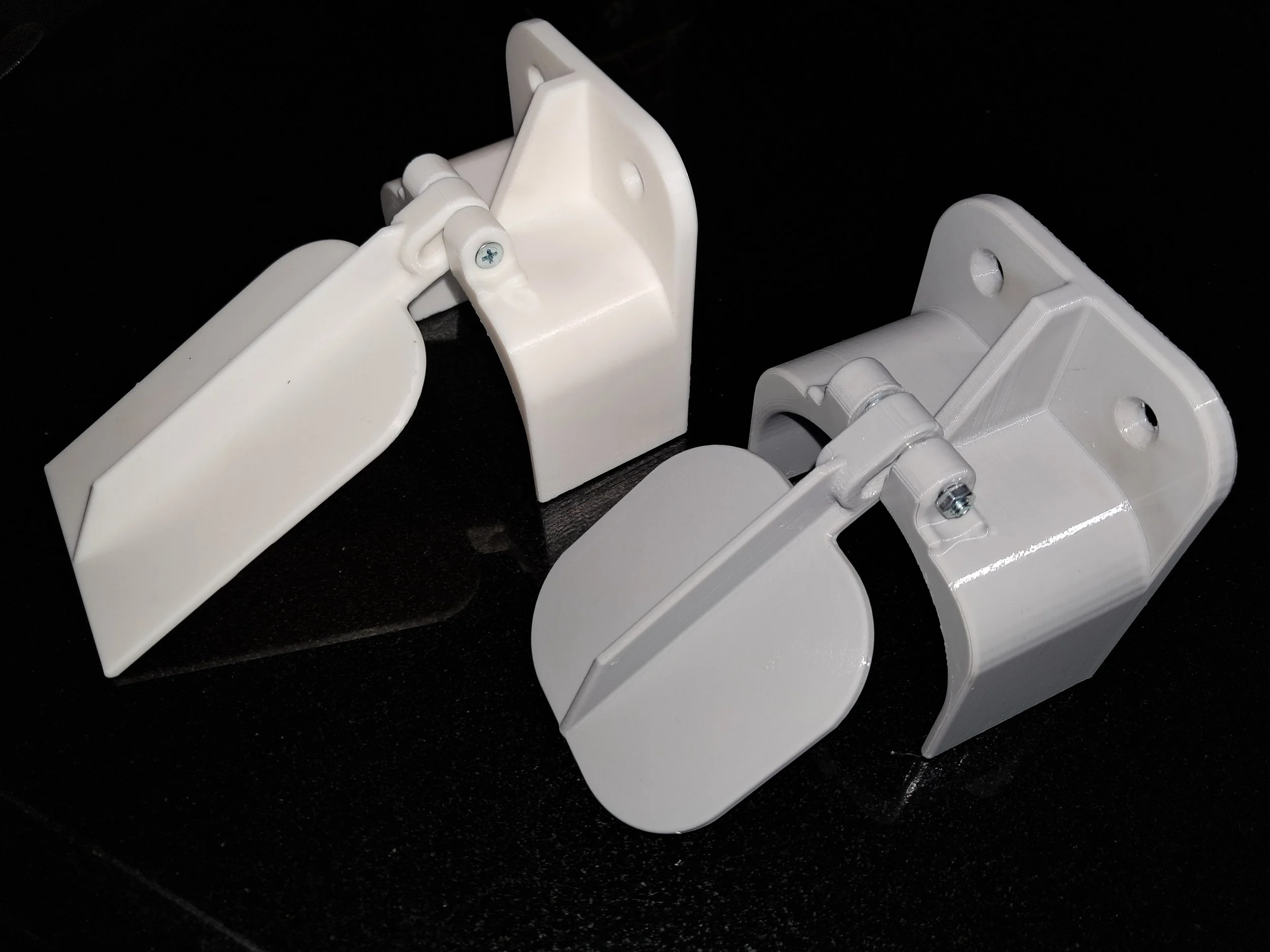 Close-up of white plastic hinges and brackets on a black surface.
