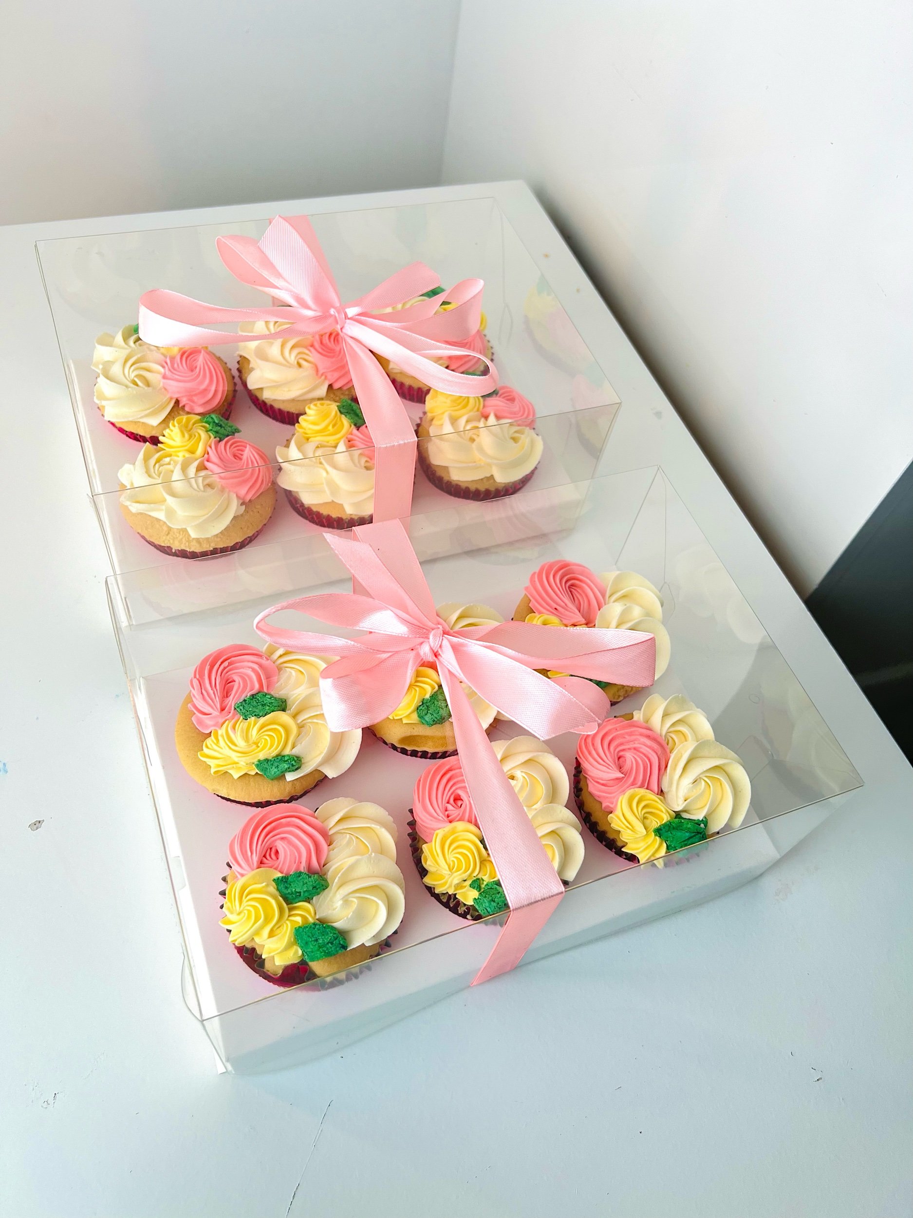 Colourful Box of 6 Cupcakes by Sensational Cakes and Desserts boxed in an elegant transparent luxury cake box with pink ribbon.