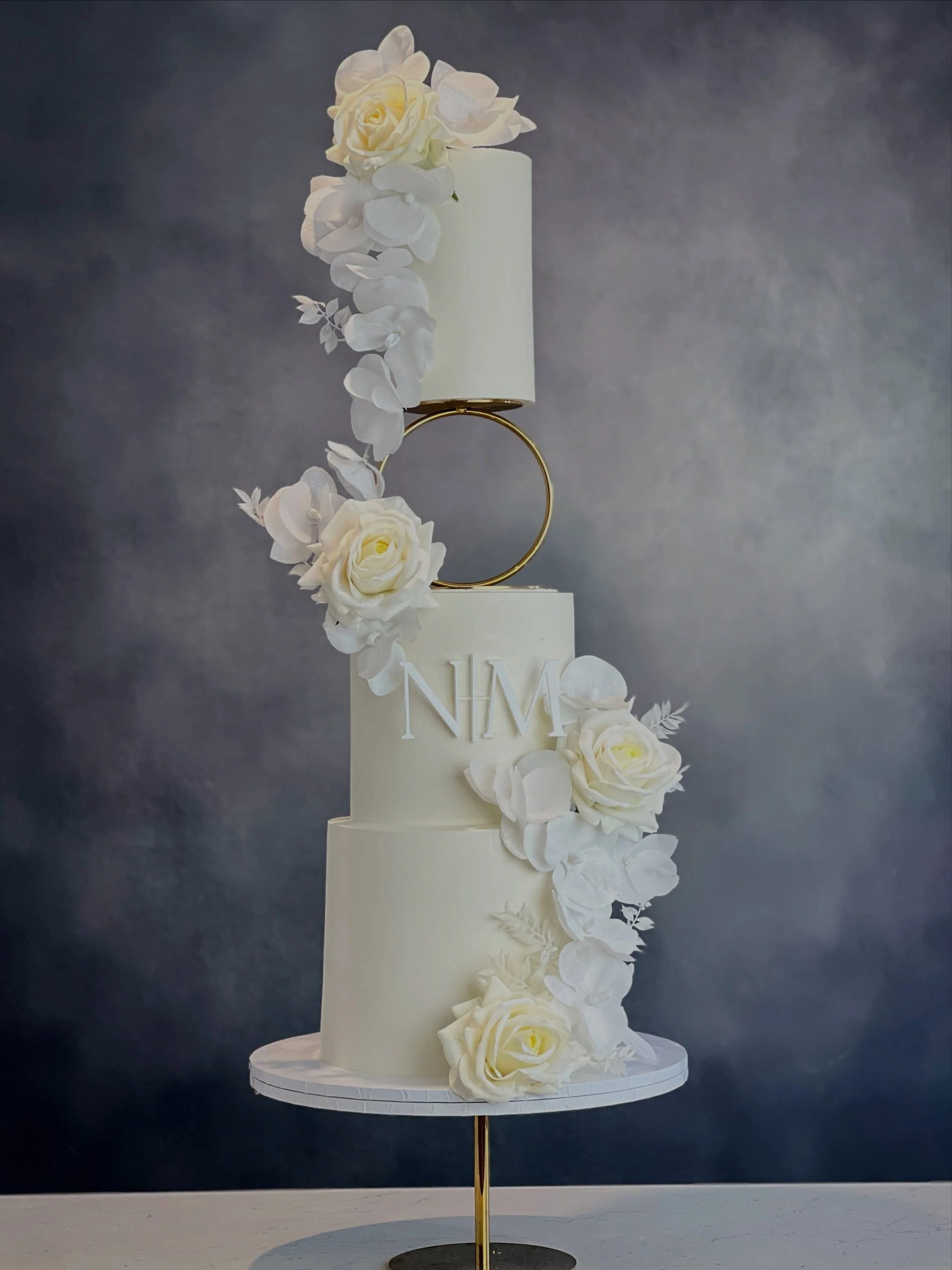 Wrapped in timeless white elegance 🤍

A statement wedding cake for Manisha &amp; Nikhil, finished in our signature silky chocolate ganache and adorned with delicate wafer paper orchids, silk orchids and soft ivory florals.

Cake spacer &amp; pedesta
