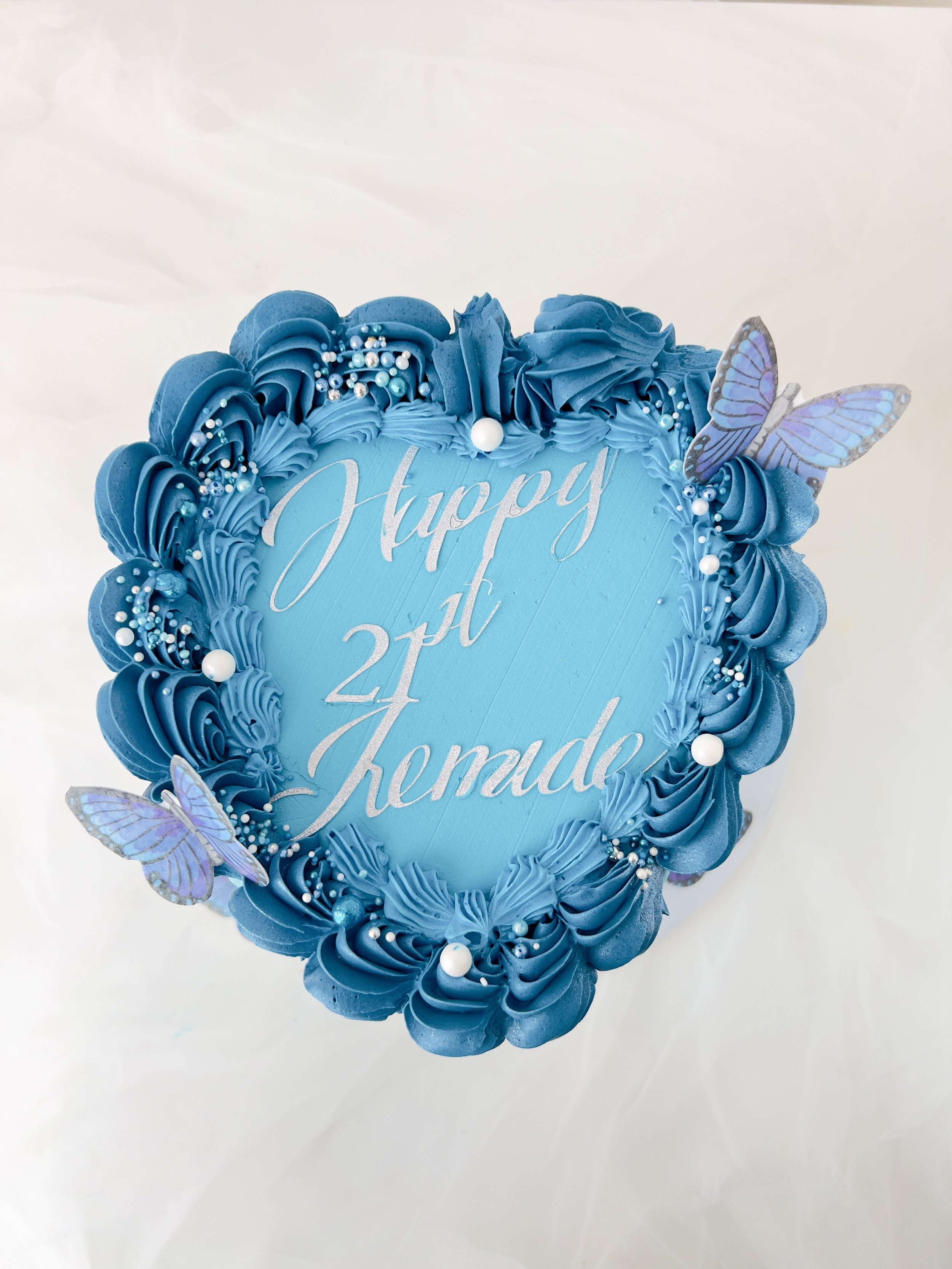 Soft Blue Vintage Heart Cake by Sensational Cakes and Desserts adorned with blue butterflies and delicately pipped buttercream.