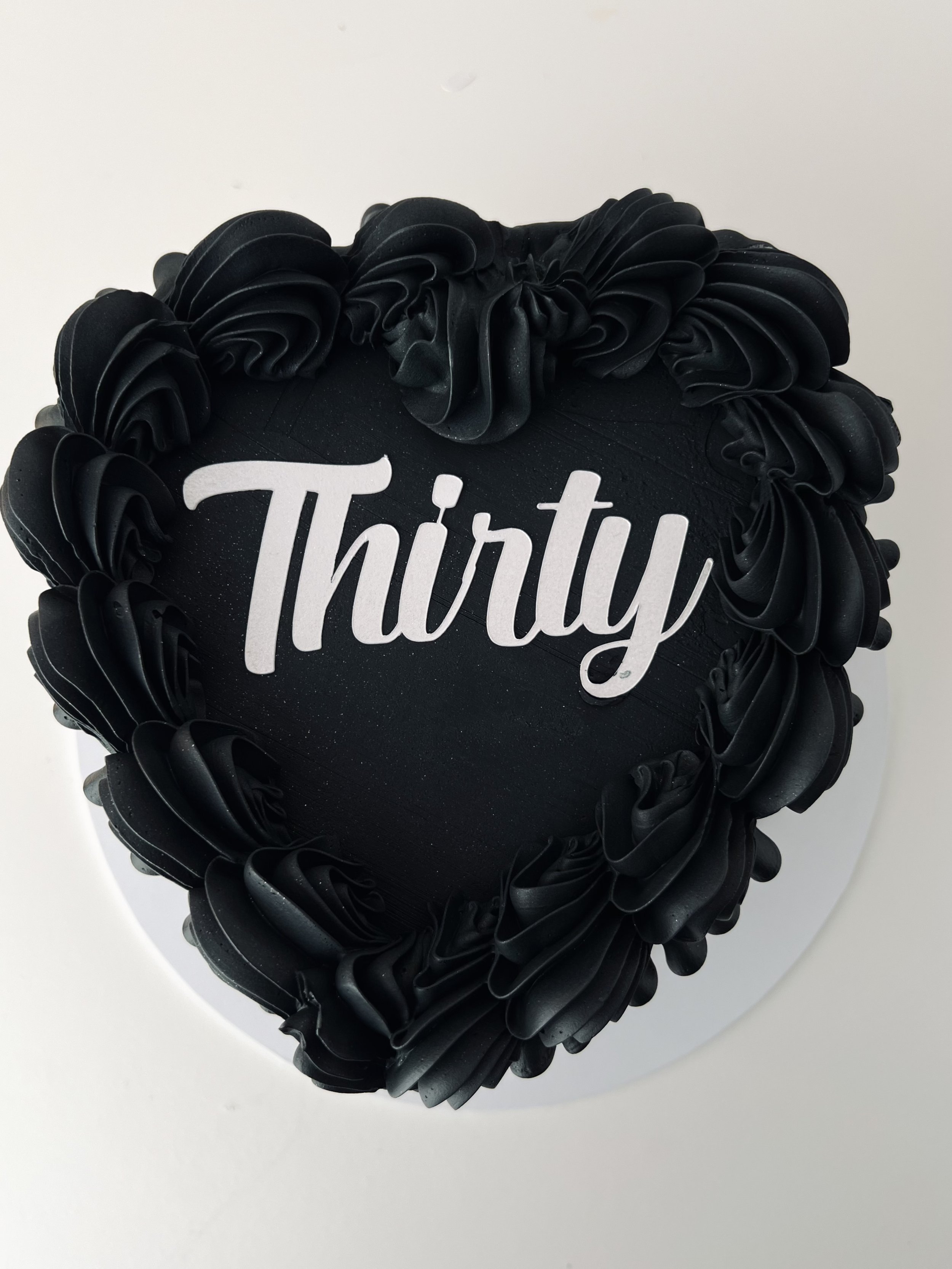 Top view of the Black Heart Cake With White Name Charm by Sensational Cakes and Desserts