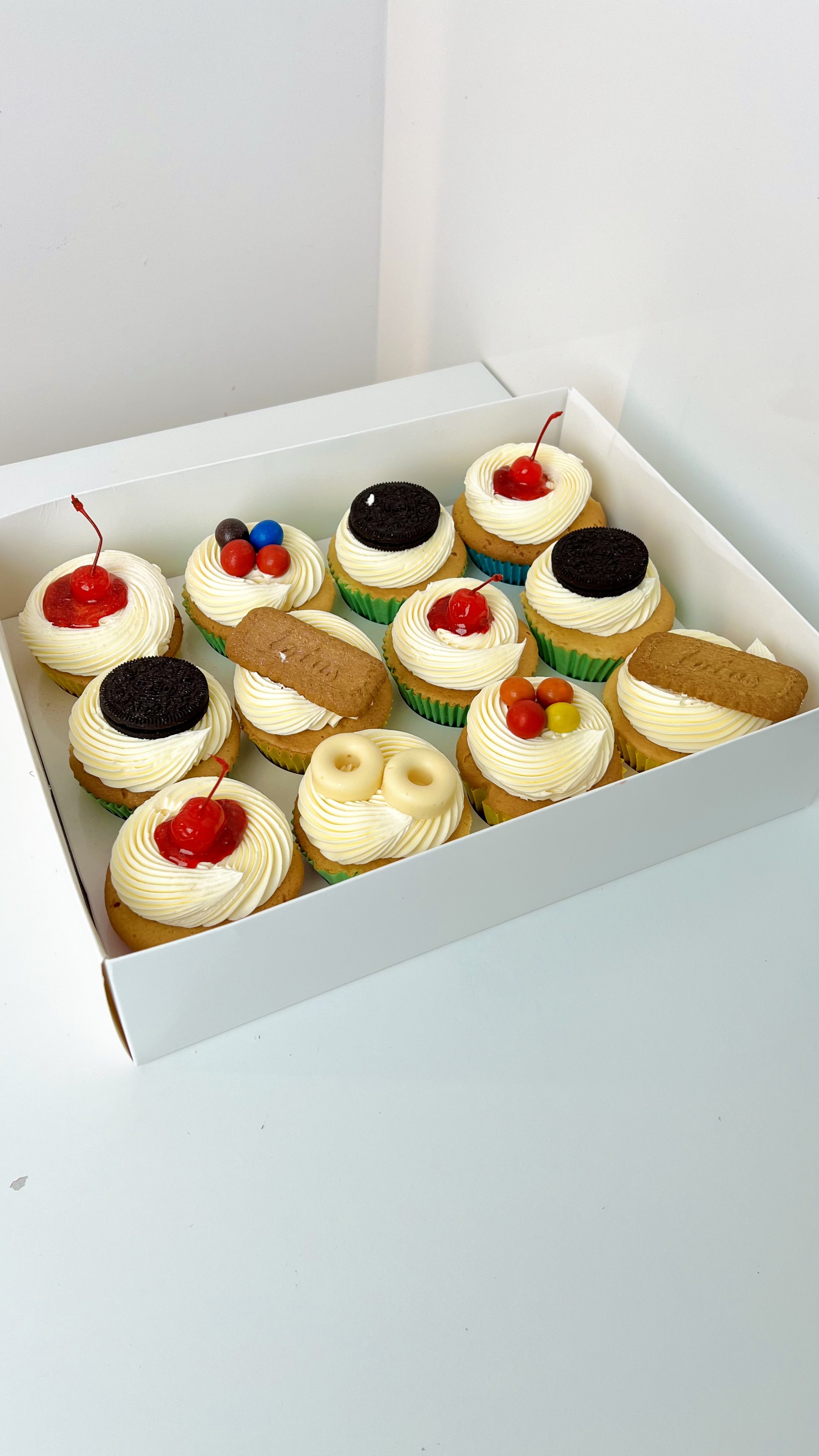 Selection Cupcakes (Box of 12) by Sensational Cakes and Desserts, featuring sugar glazed cherry, Oreo chocolate and Loftus Biscoff toppings.