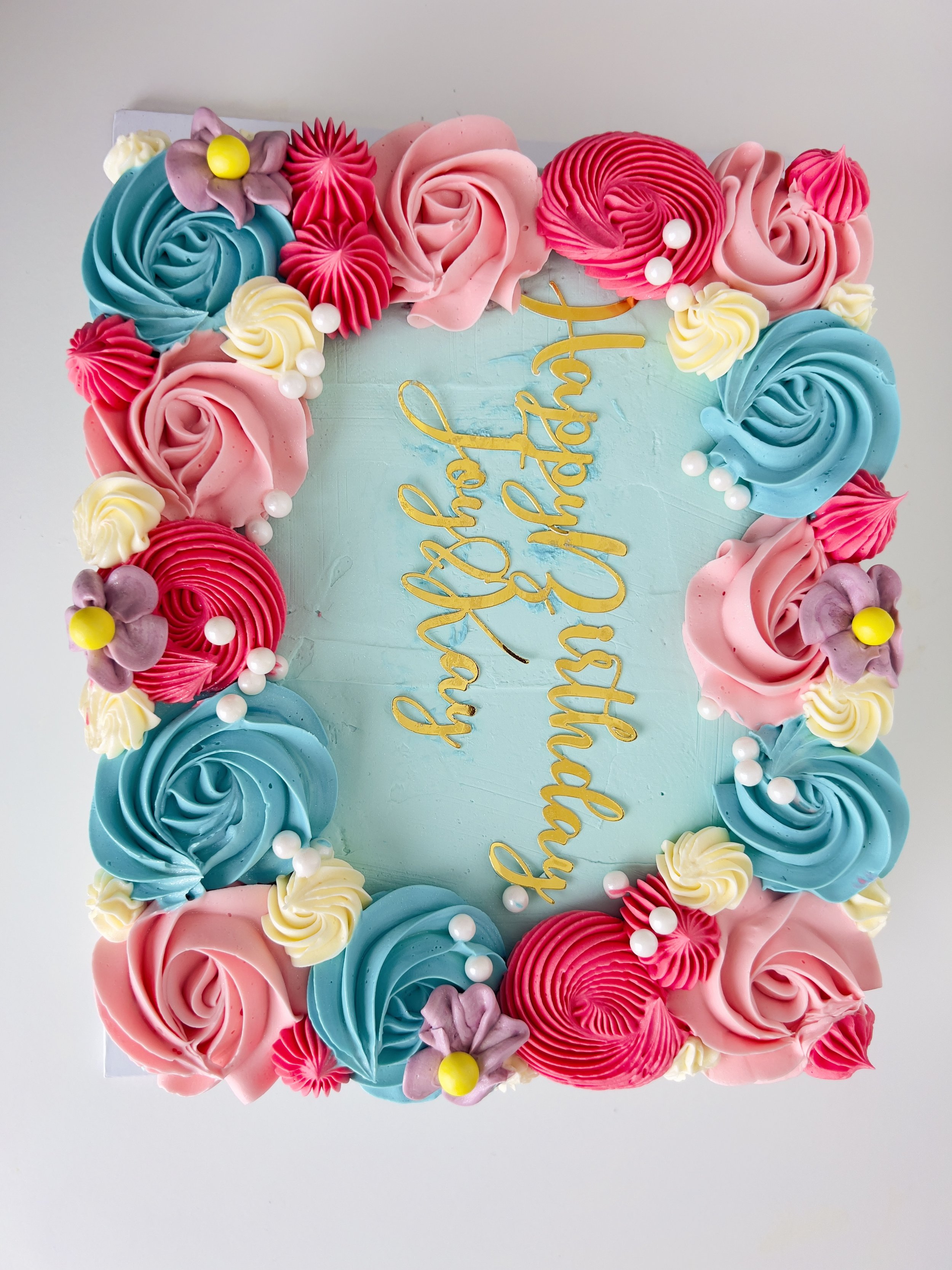 Sensational Cakes and Dessert's turquoise sheet cake is adorned with multi colourful, delicately piped swirls.