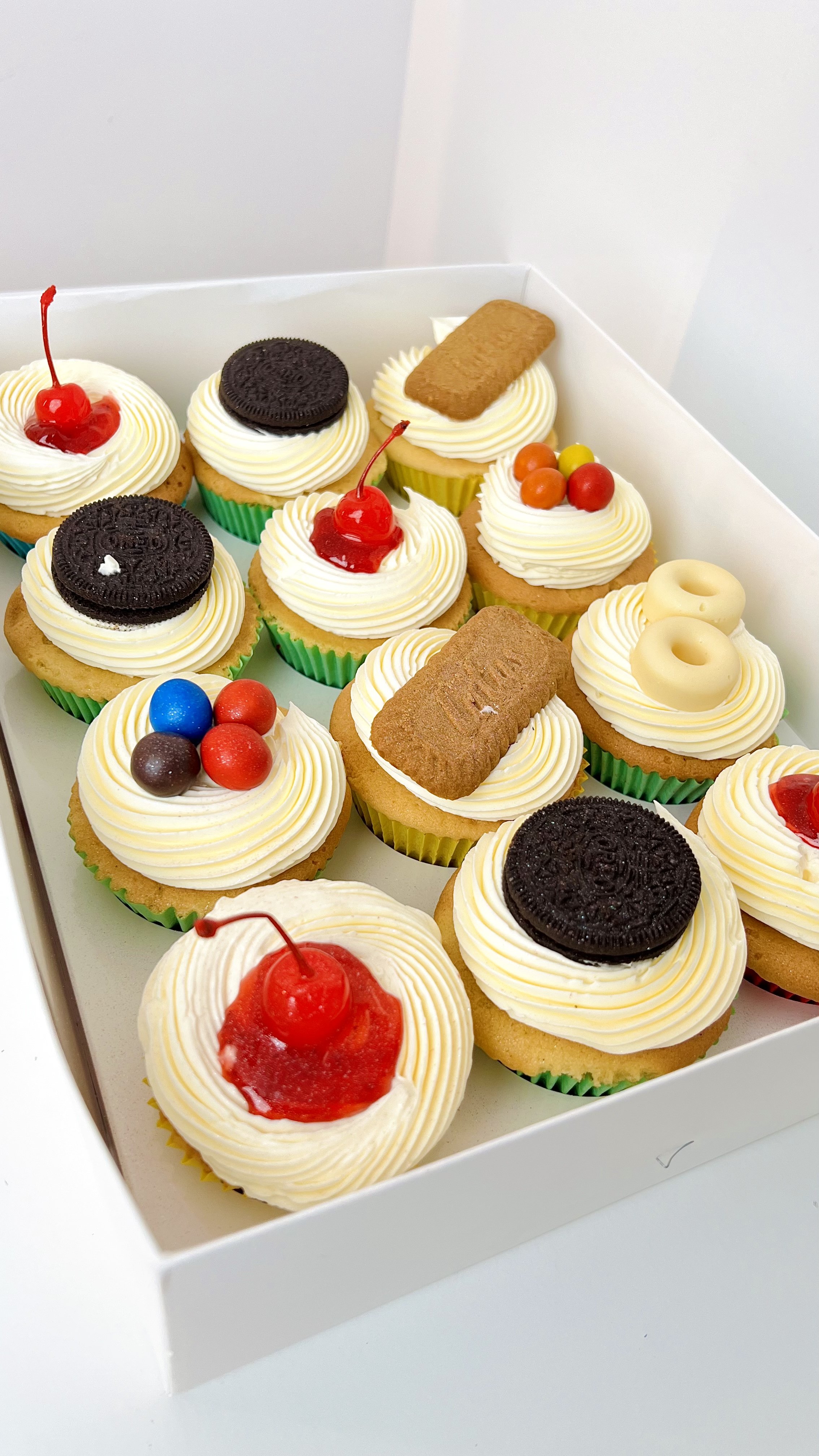 Selection Cupcakes (Box of 12) by Sensational Cakes and Desserts, featuring sugar glazed cherry, Oreo chocolate and Loftus Biscoff toppings.