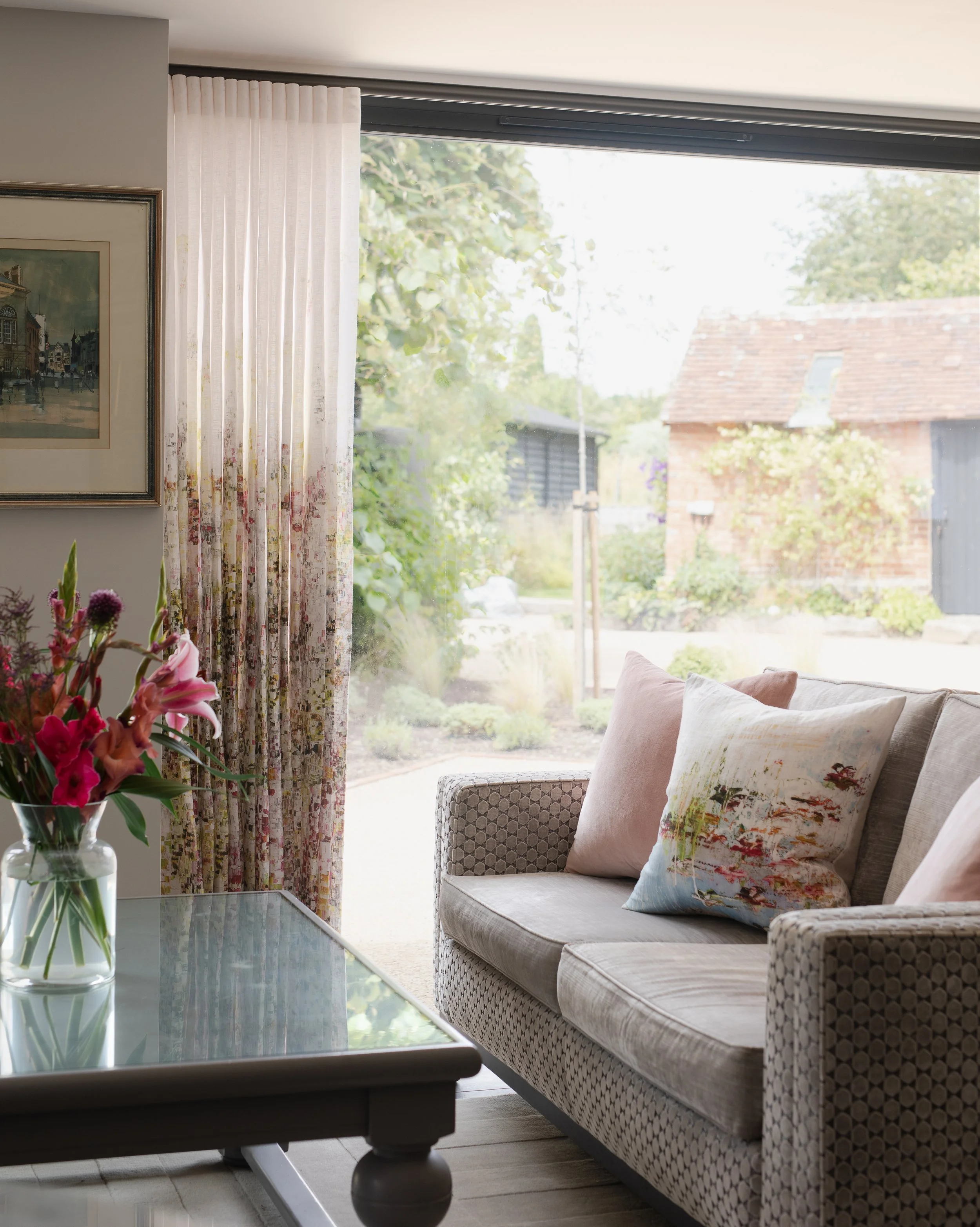 Living room in soft pastels of pale pink and soft blue, english meadow garden print on curtains
