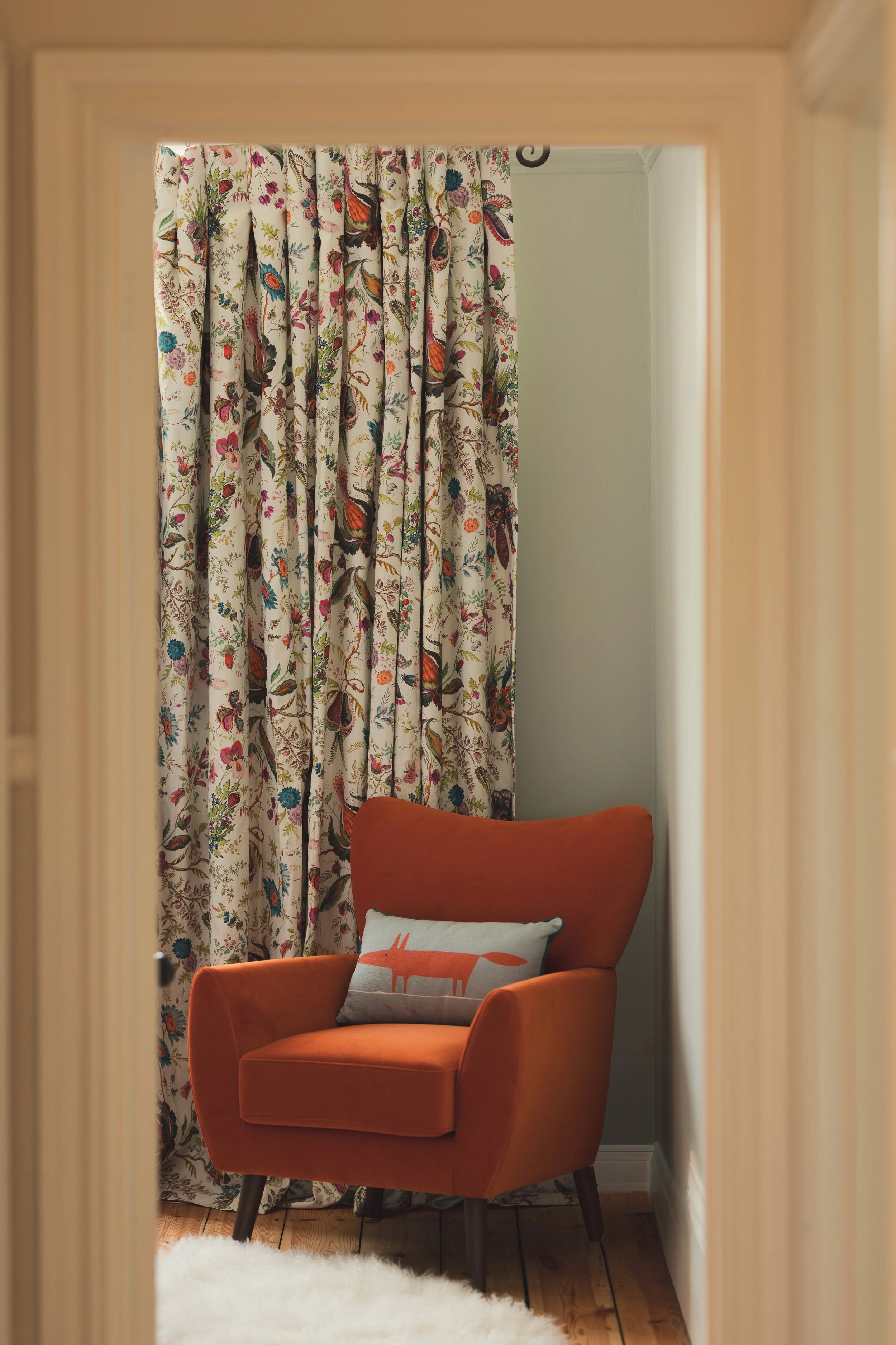 Doorway view into bedroom with chair and bright floral curtains.jpg