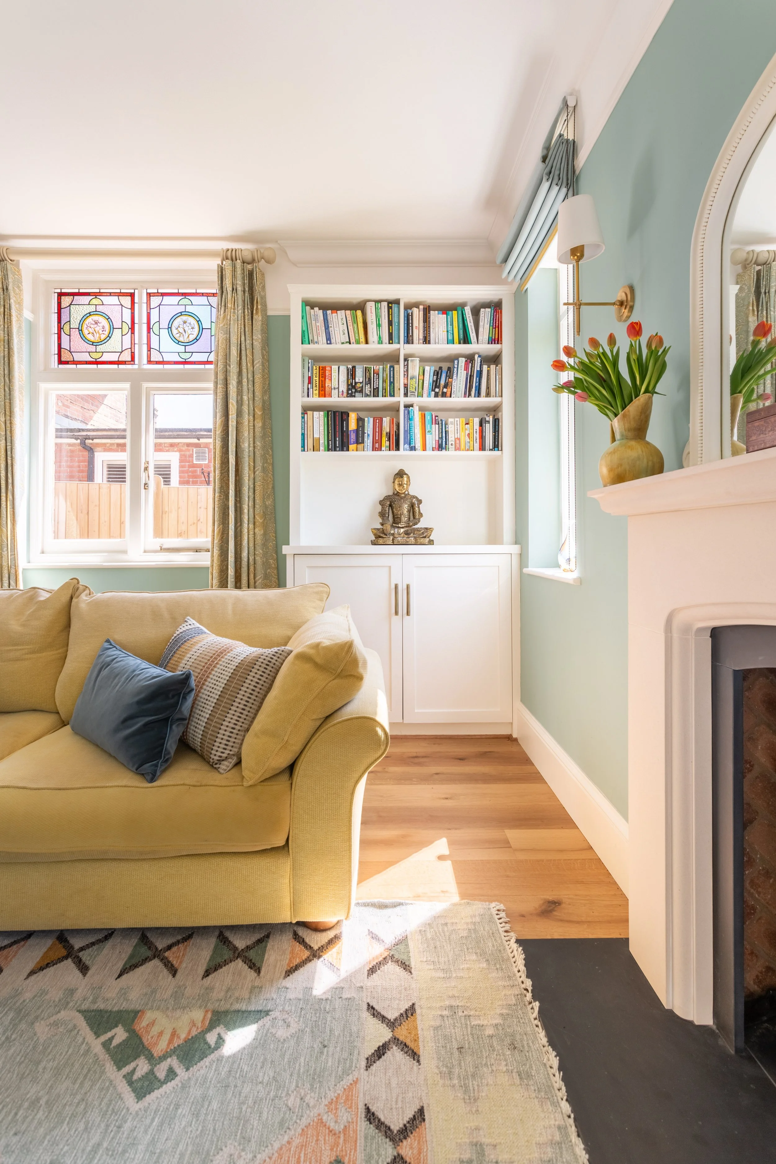 Light bright living room space, duckegg blue walls, white bookcase, white fireplace.