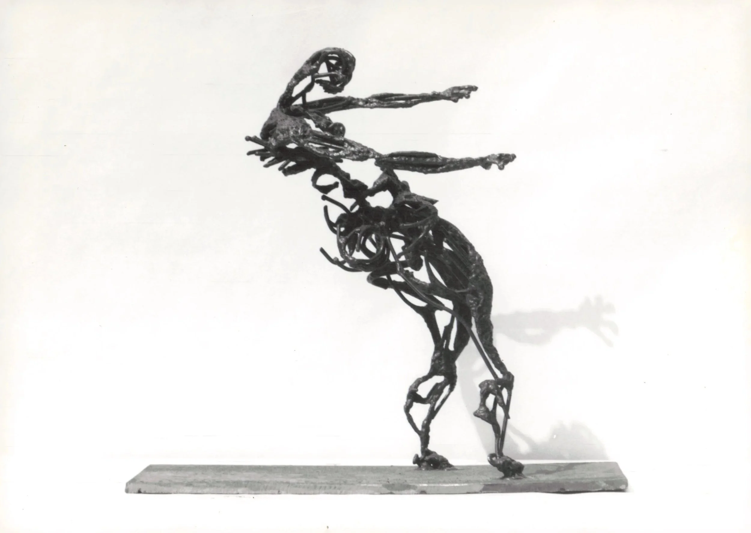 A black metal sculpture of a horse and rider, with the rider pointing forward, mounted on a rectangular base.