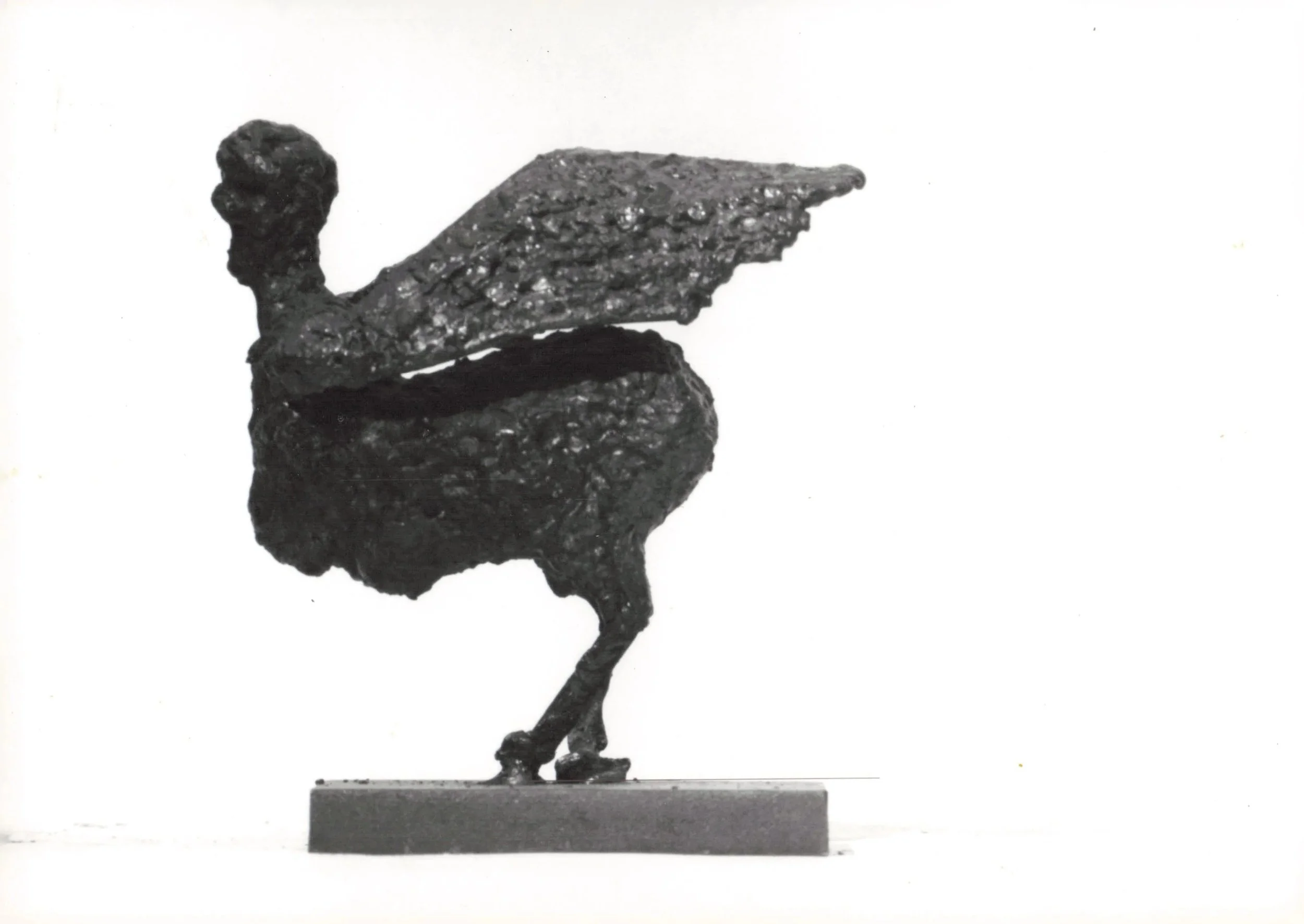 A small metallic sculpture of a bird, likely an oriole, standing on a rectangular base. The bird has an elongated body, a rounded head, and a long tail. The artwork is painted in a dark color, possibly black.