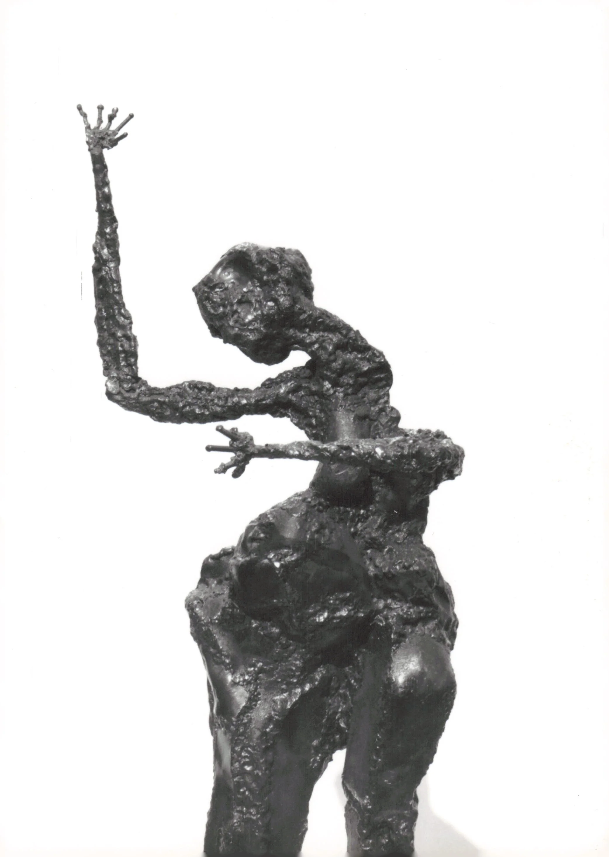 Black and white sculpture of a person with one arm raised, head tilted downward, sitting on a rocky base.