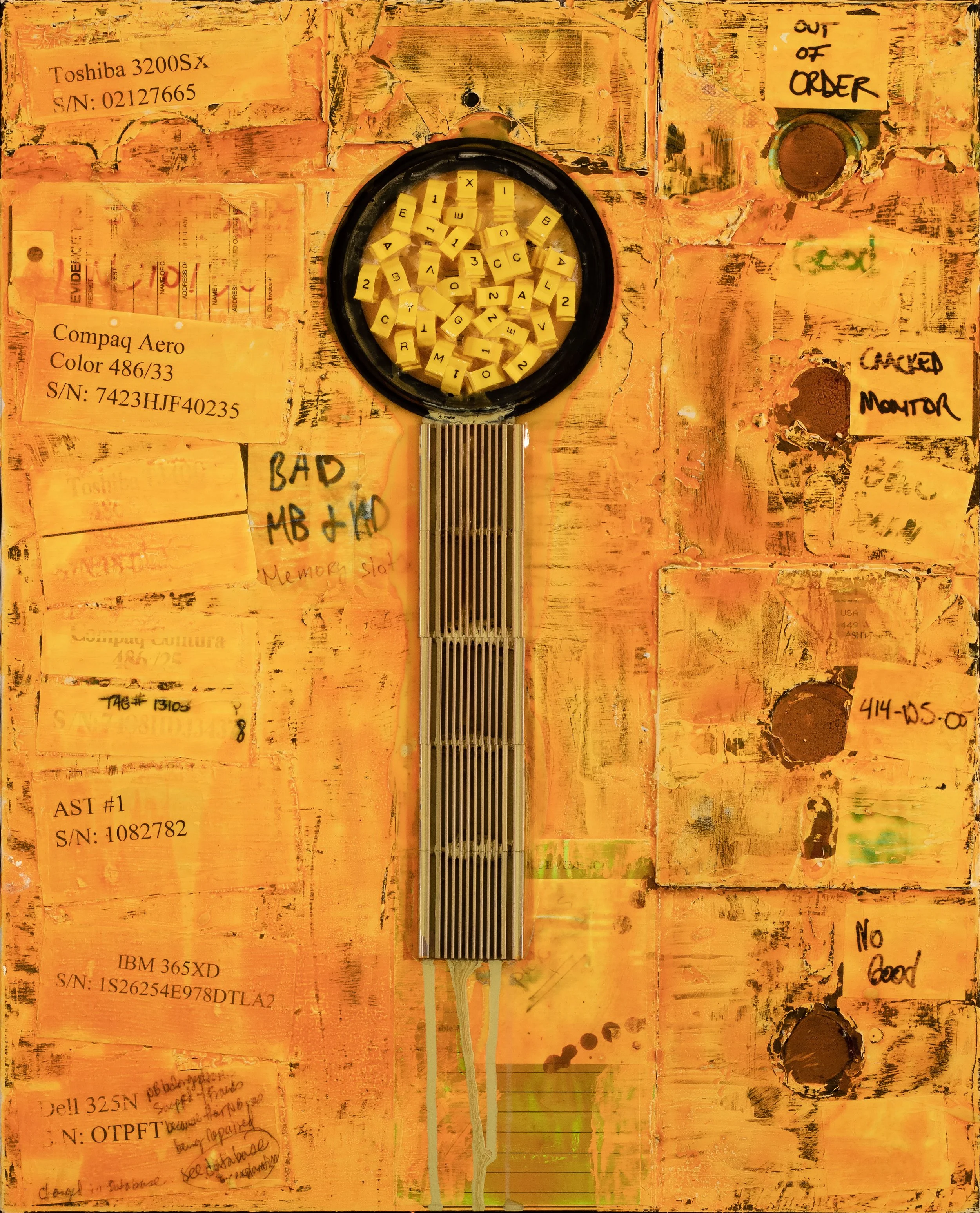 A cluttered, textured orange surface with various notes and labels attached. A circular container in the center holds yellow keyboard keys with black letters and numbers. Several labels include technical equipment descriptions, serial numbers, and ha