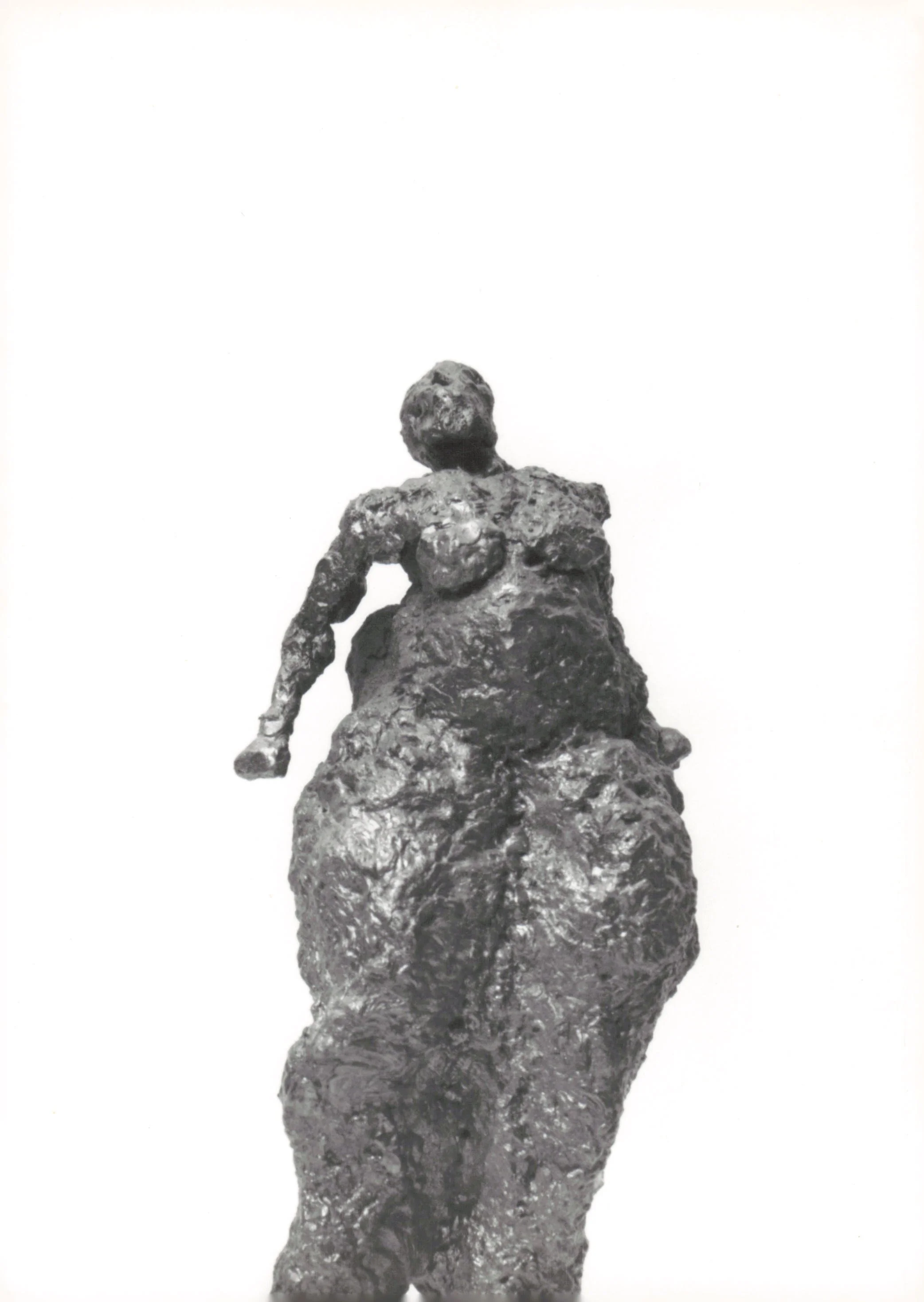 Black and white sculpture of a woman with a large, textured base, looking upwards, made of rough, metallic material.