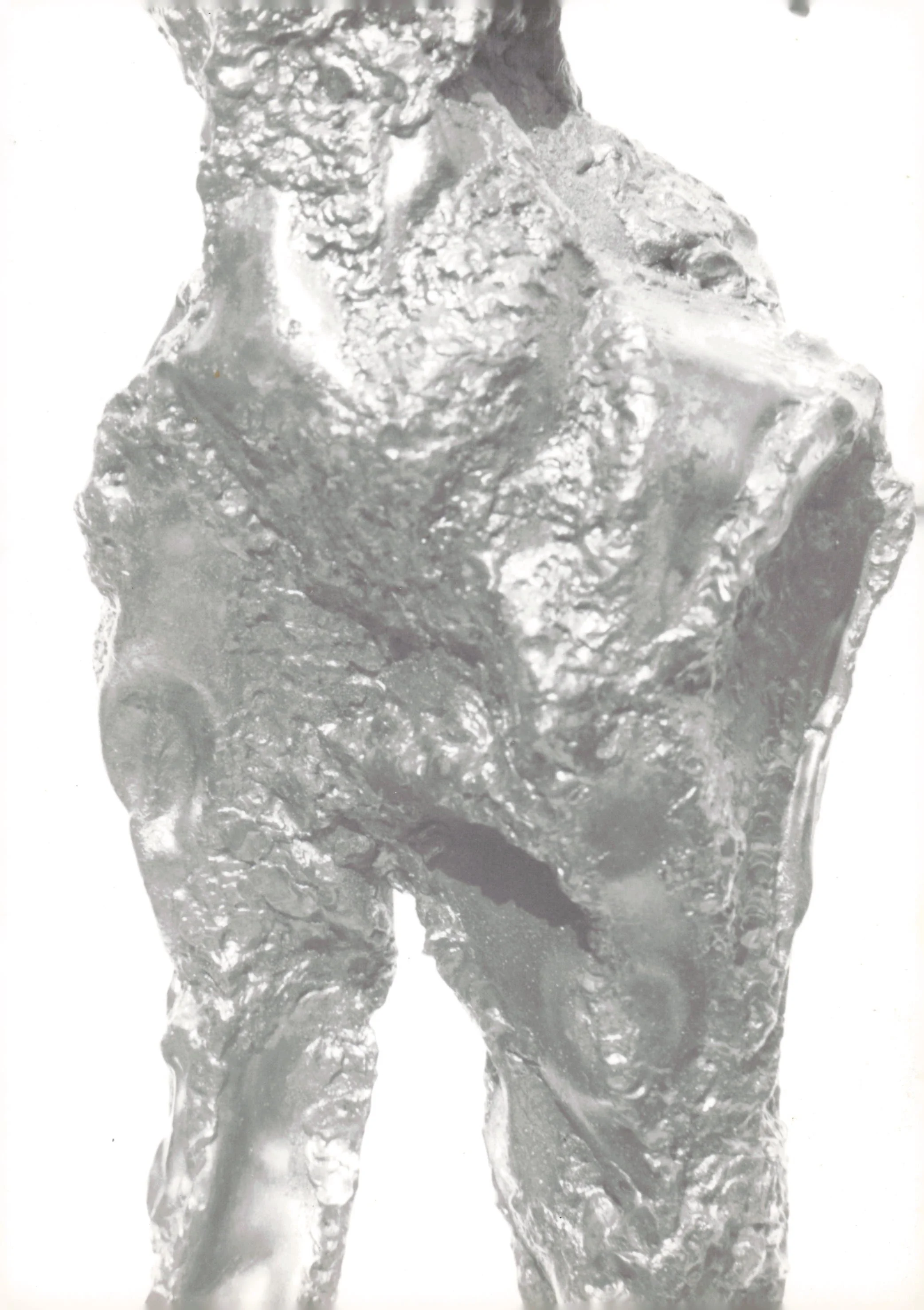 A close-up of a metallic sculpture of a seated dog in a reflective, shiny surface.