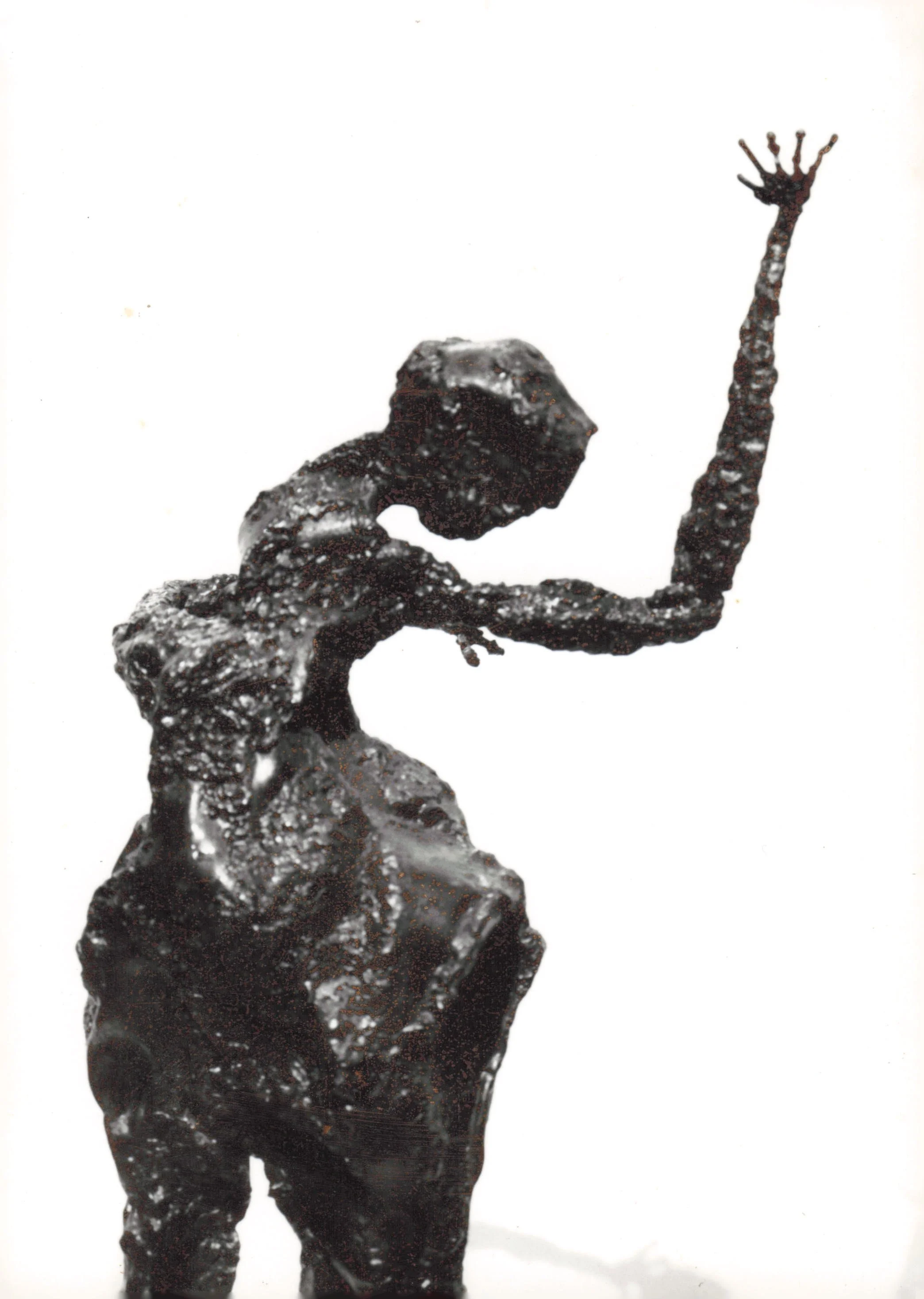 Sculpture of a hand and arm with extended fingers, made from a dark, textured material, set against a plain background.