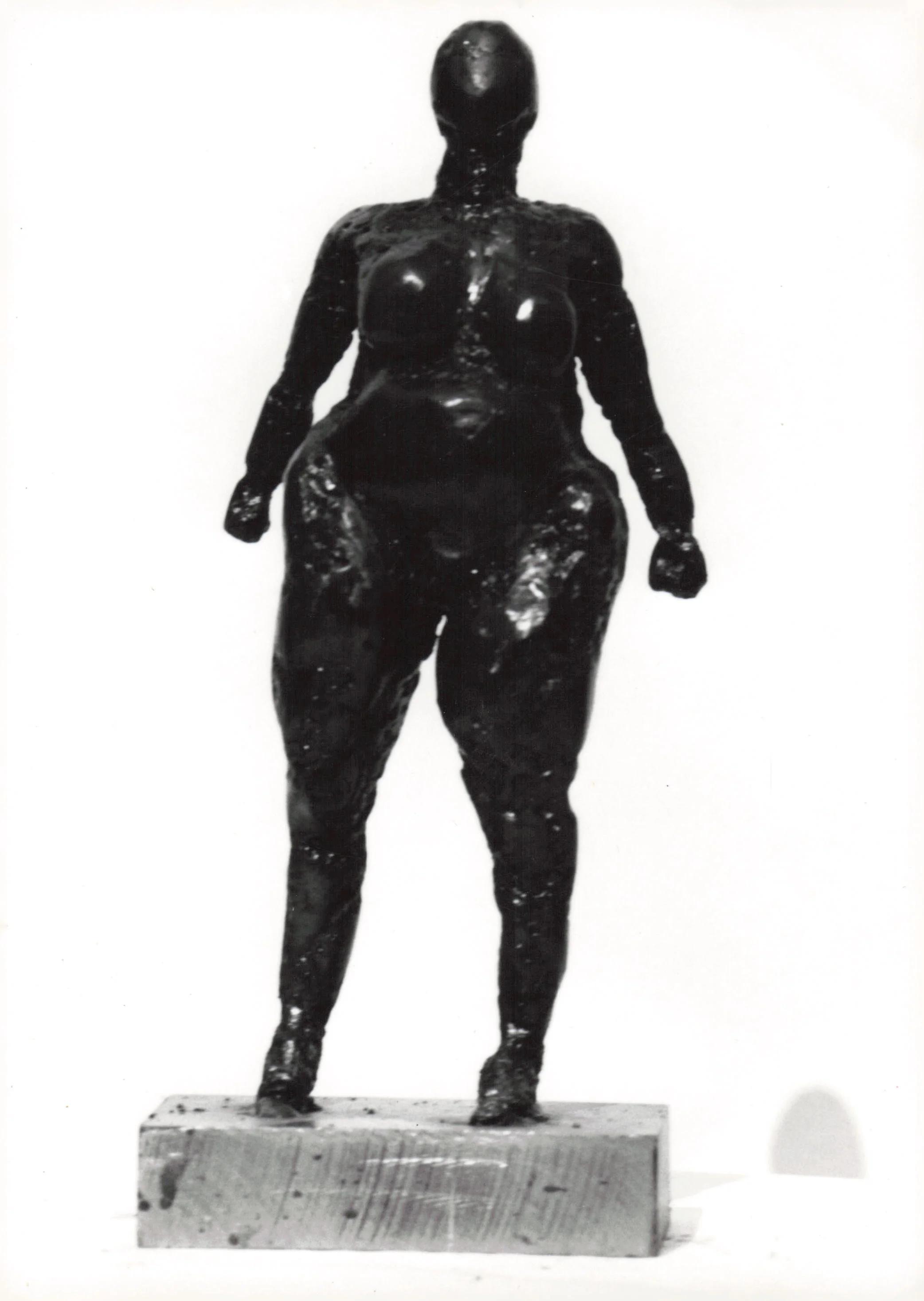 Black sculpture of a standing male figure on a rectangular base.