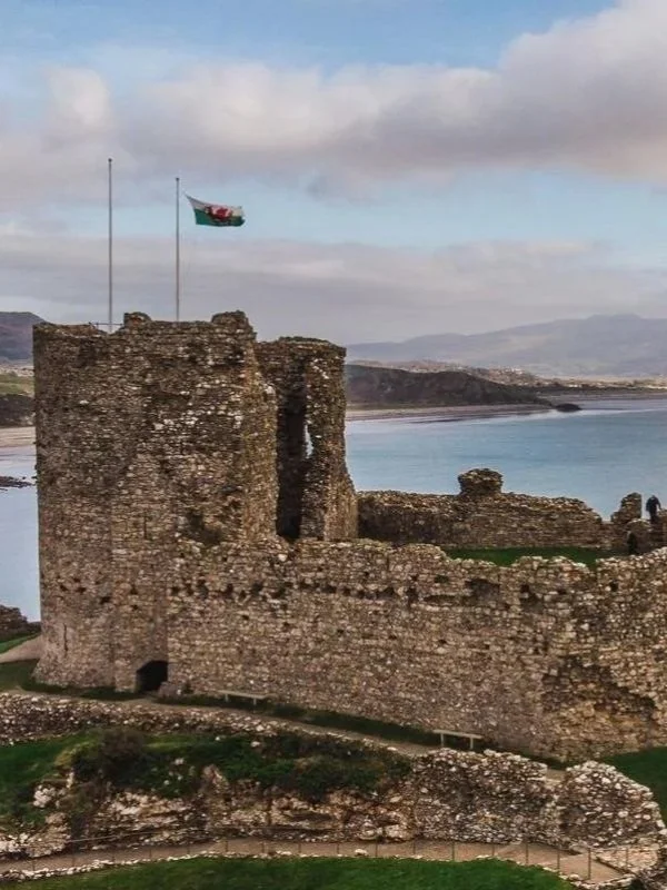 cricieth castle with welsh flag and the sea and mountains in the background