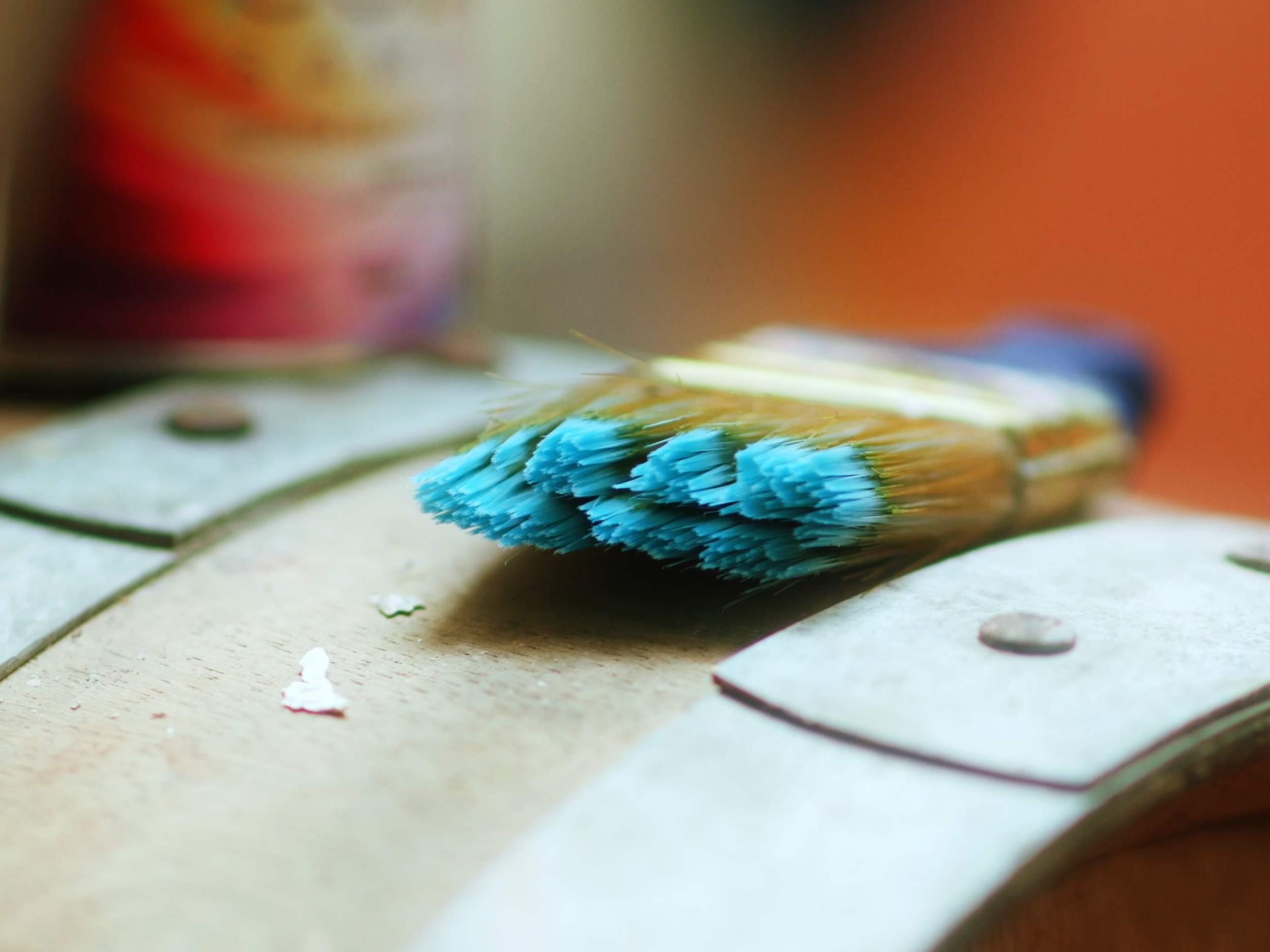 Beau Kester Cinematographer  Close-up of a paintbrush with blue bristles resting on a wooden surface.