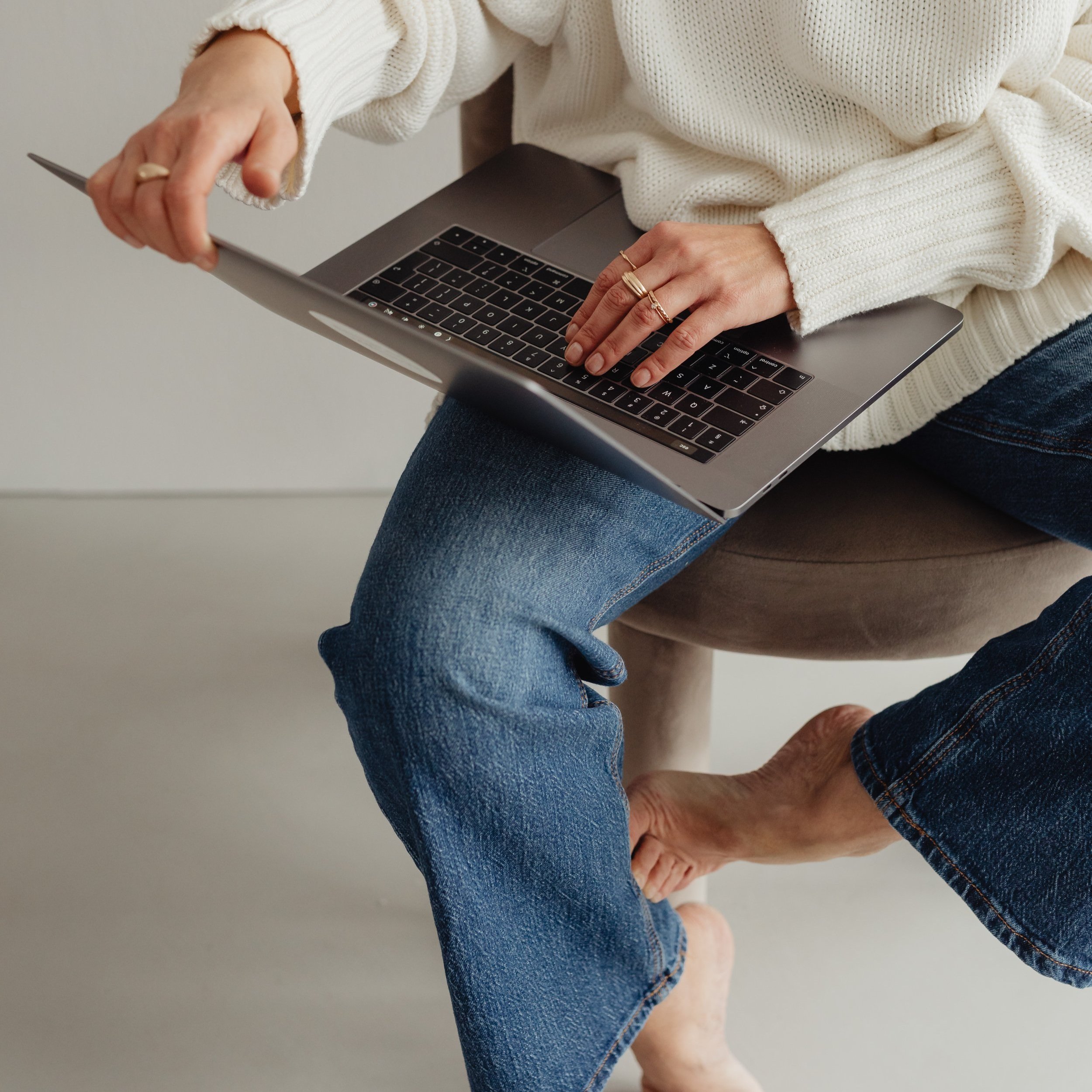 kaboompics_woman-in-white-sweater-gold-rings-jewelry-jeans-laptop-work-29450.jpg