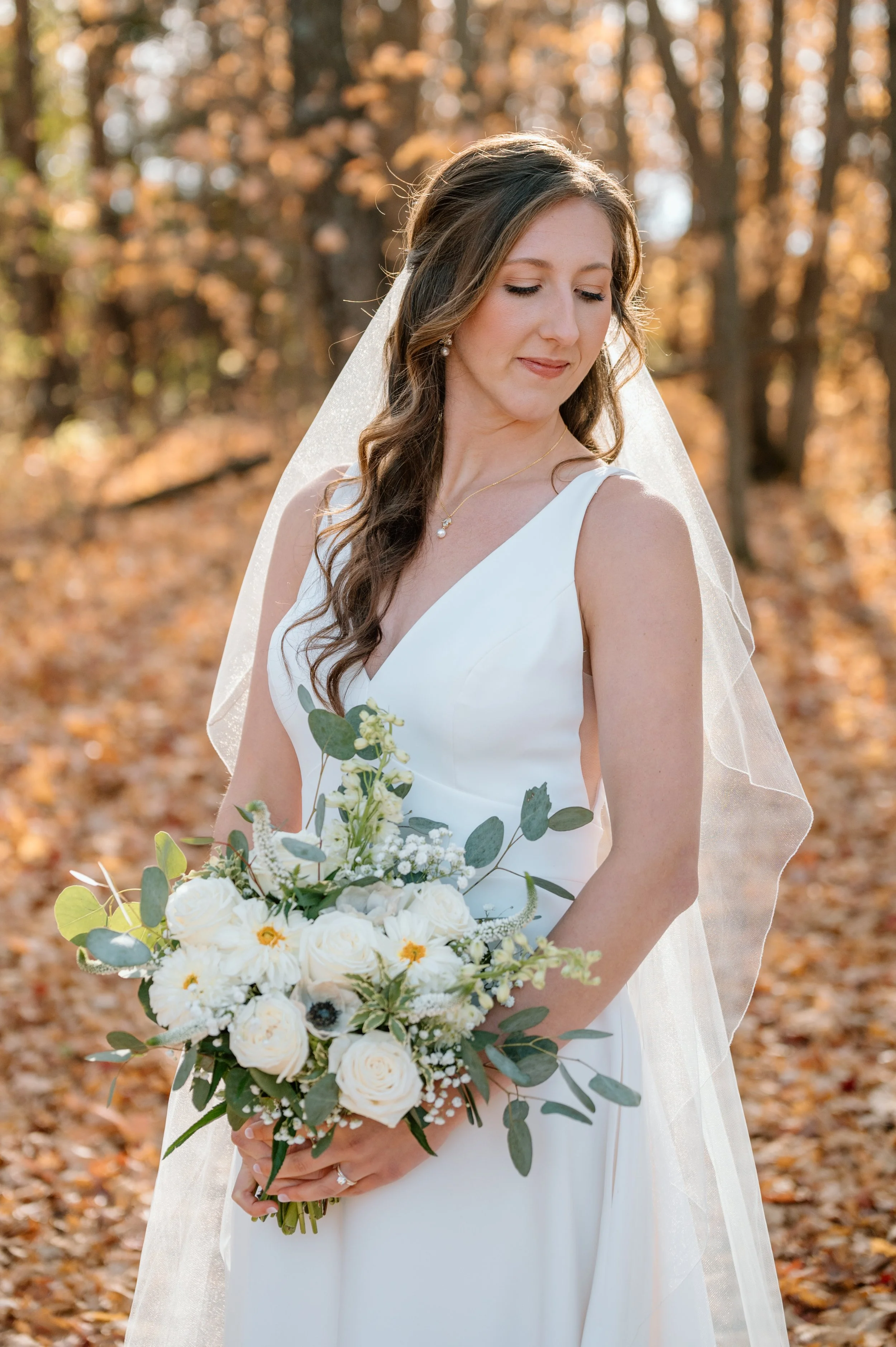 MN Horse and Hunt Club bride backlight by the sun as she holds her white bouquet with eucalyptus