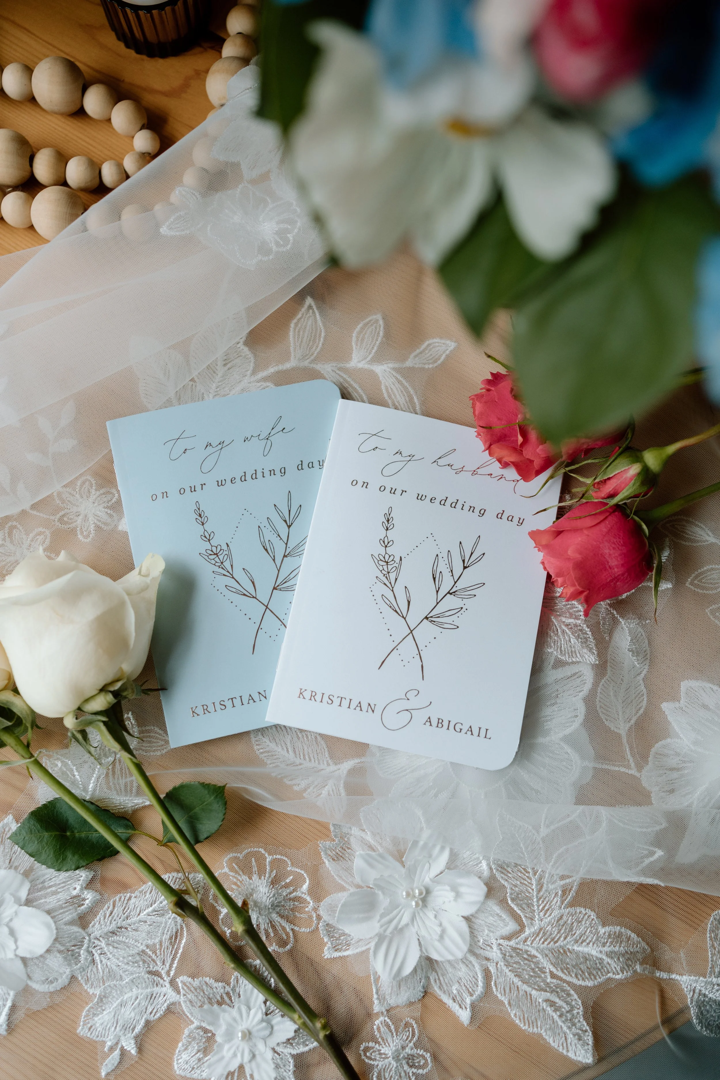 Personal vow books sit on top of bride's floral veil on MN Gensis Ranch wedding day