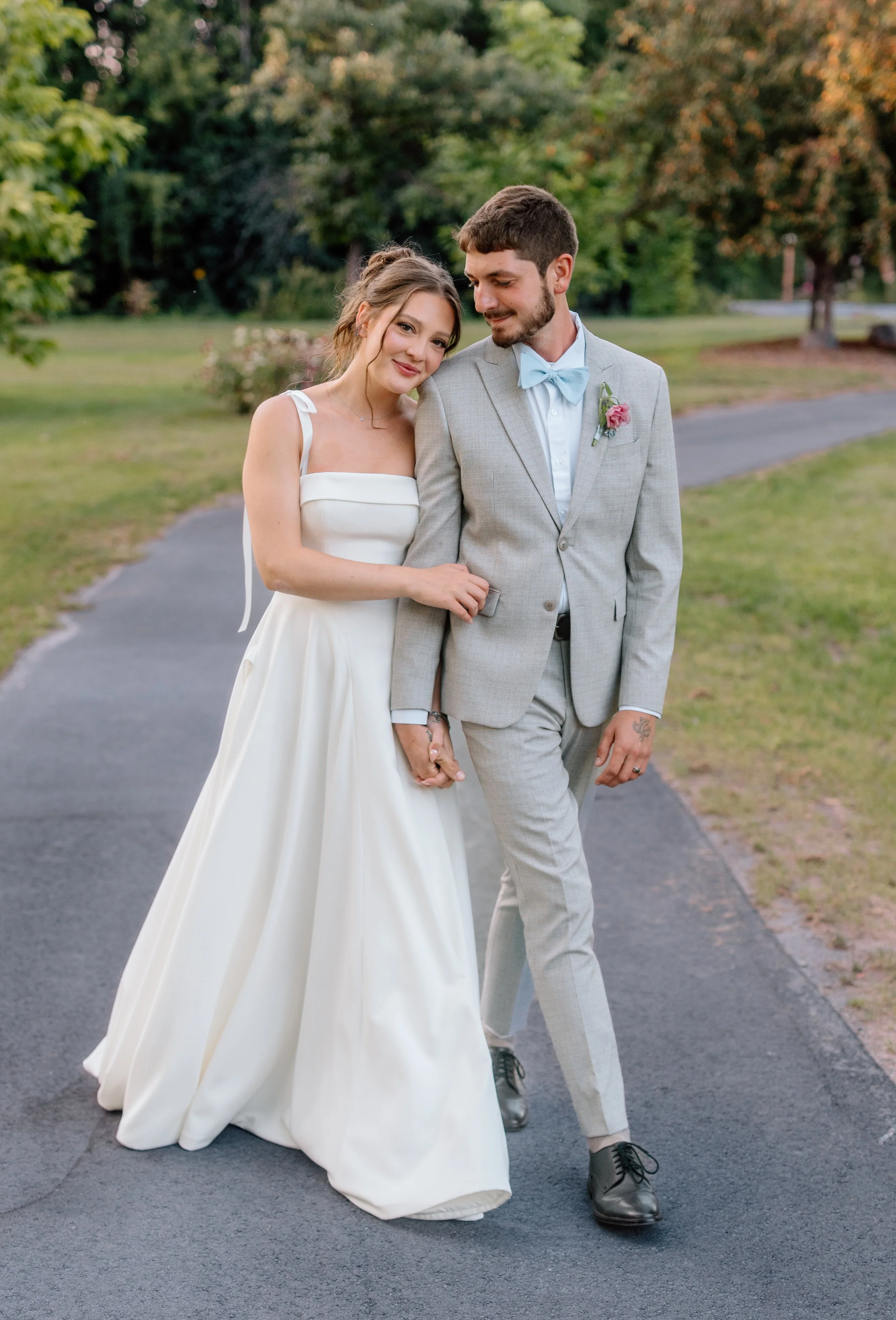 Bride and groom walk hand in hand down a path at sunset on their wedding day at the Hutton House