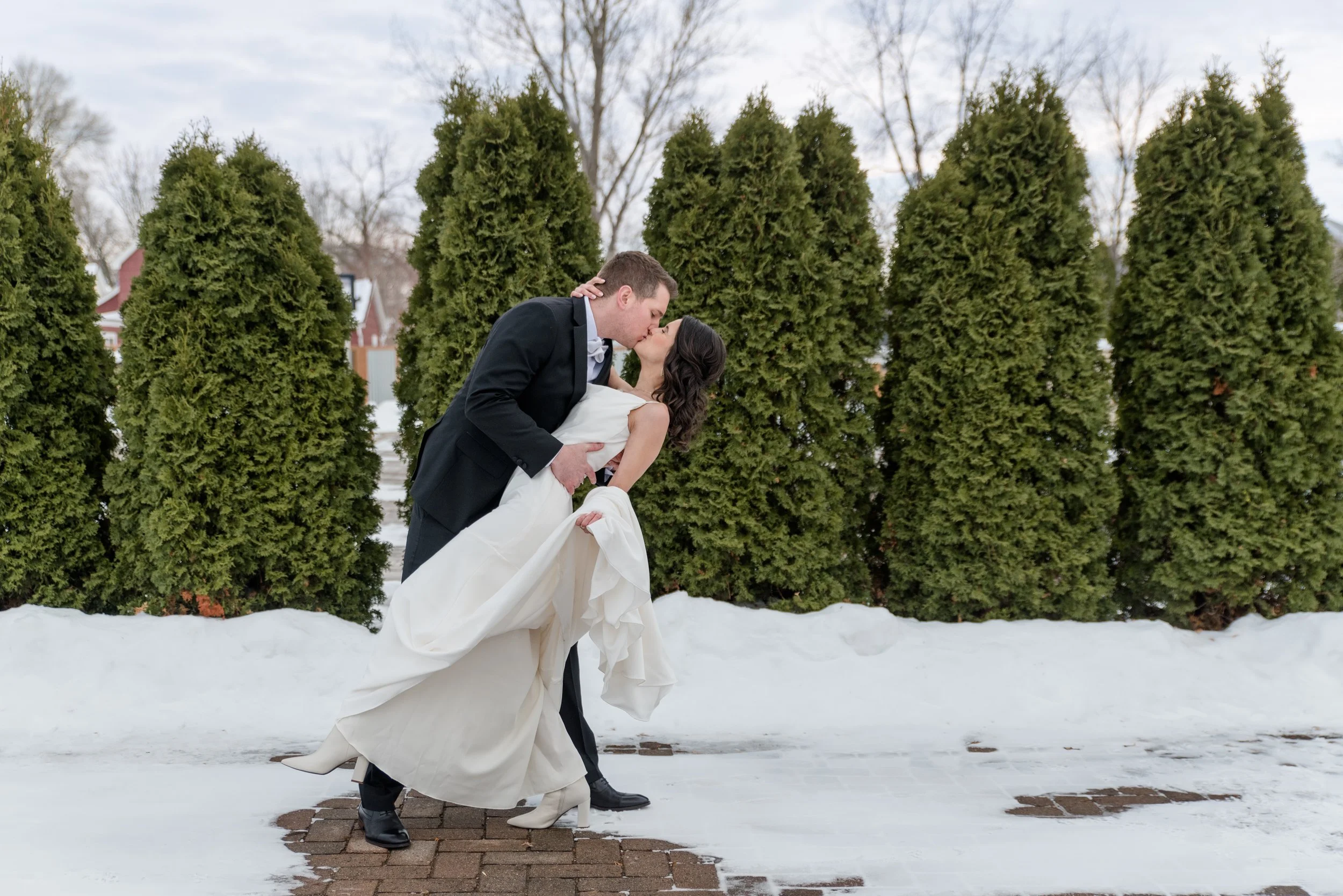 Bride and groom share a dip kiss in the snow on their New Year's Eve wedding at The Broz Event Venue in New Prague, MN