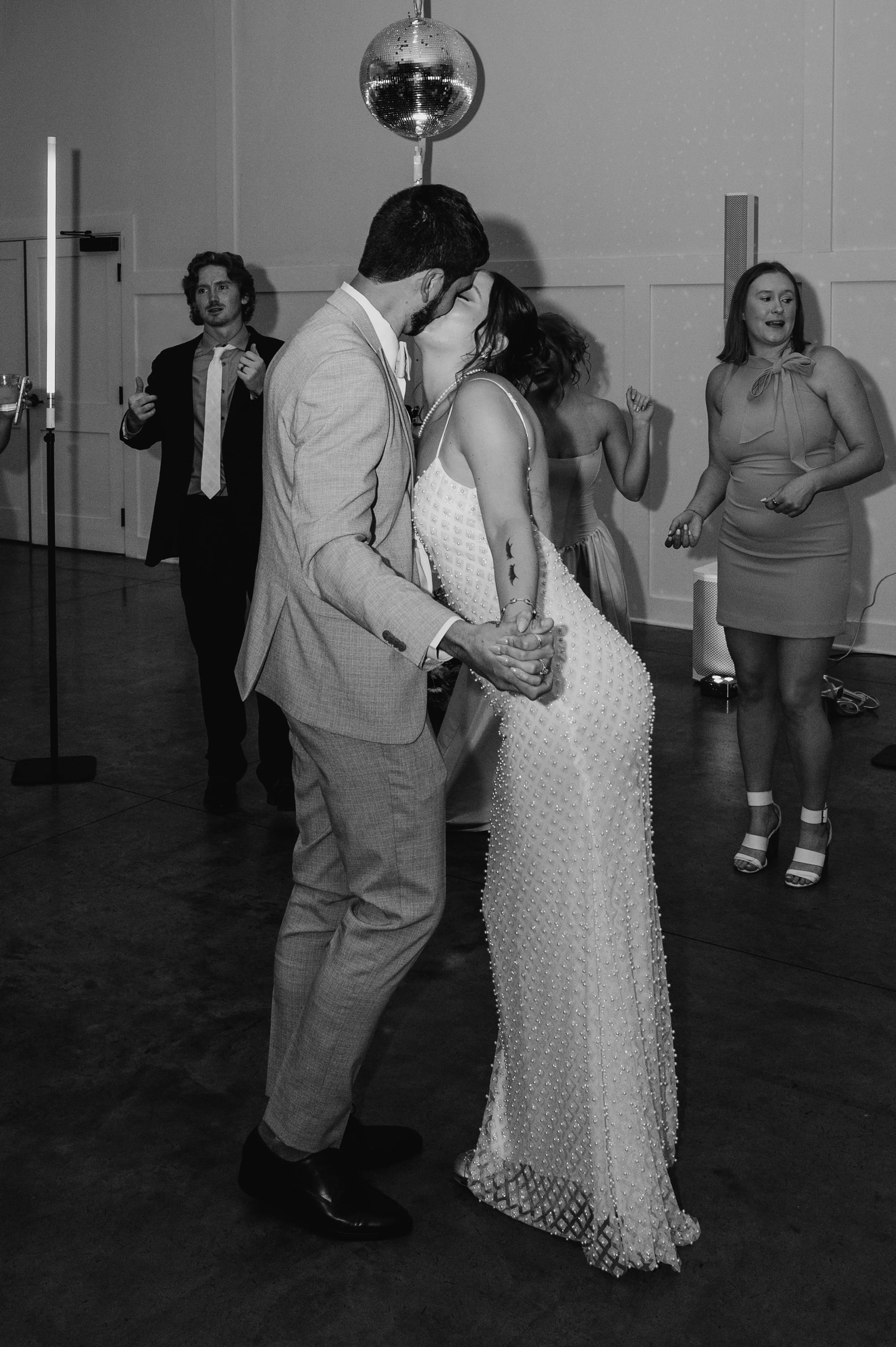 Black and white flash photo of bride and groom kissing in the middle of the dance floor at the Hutton House in Medicine Lake, MN