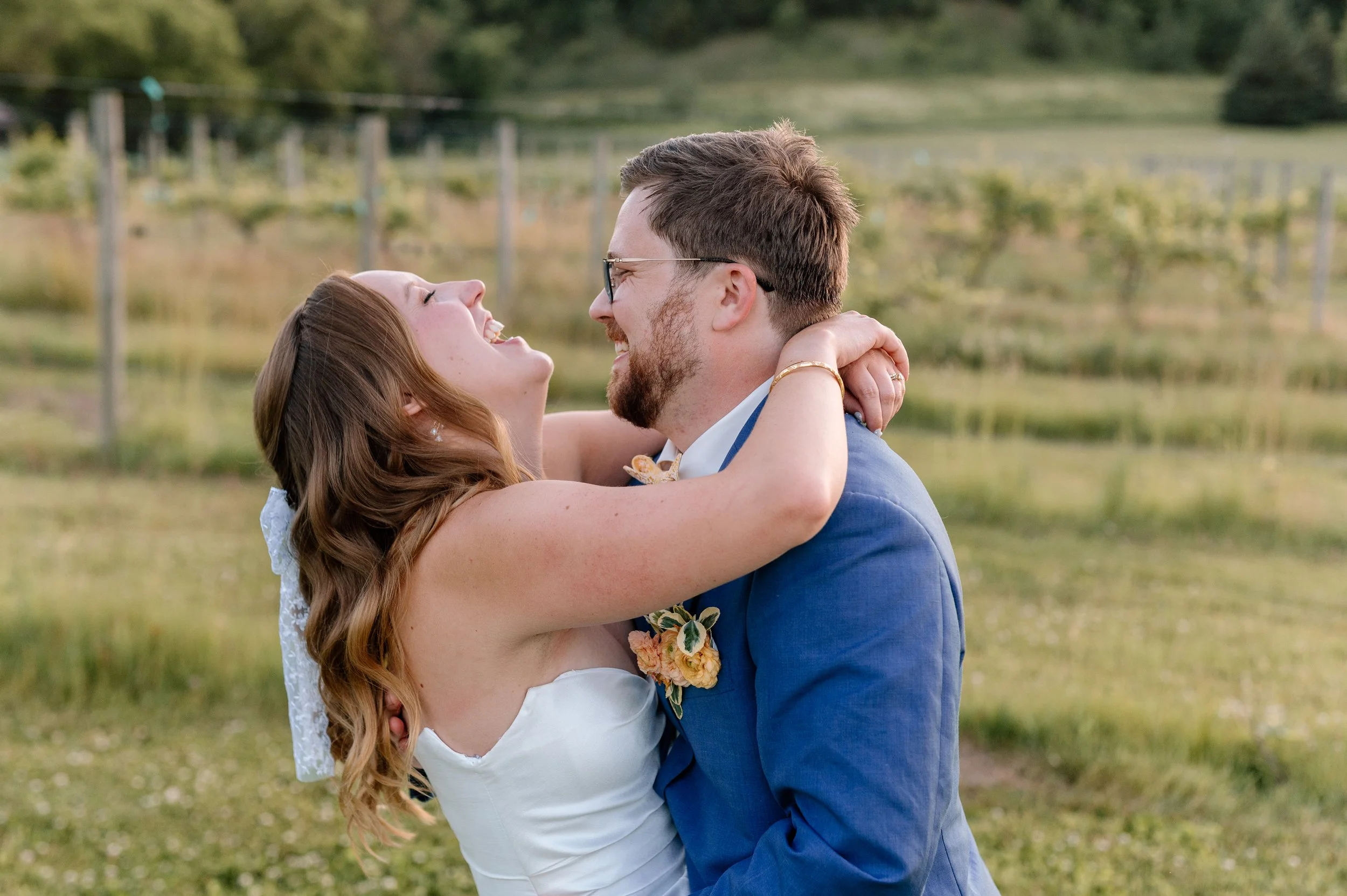 Bride and groom laugh together in front of the vines at Belle Ame on their June wedding day near the Twin Cities metro area