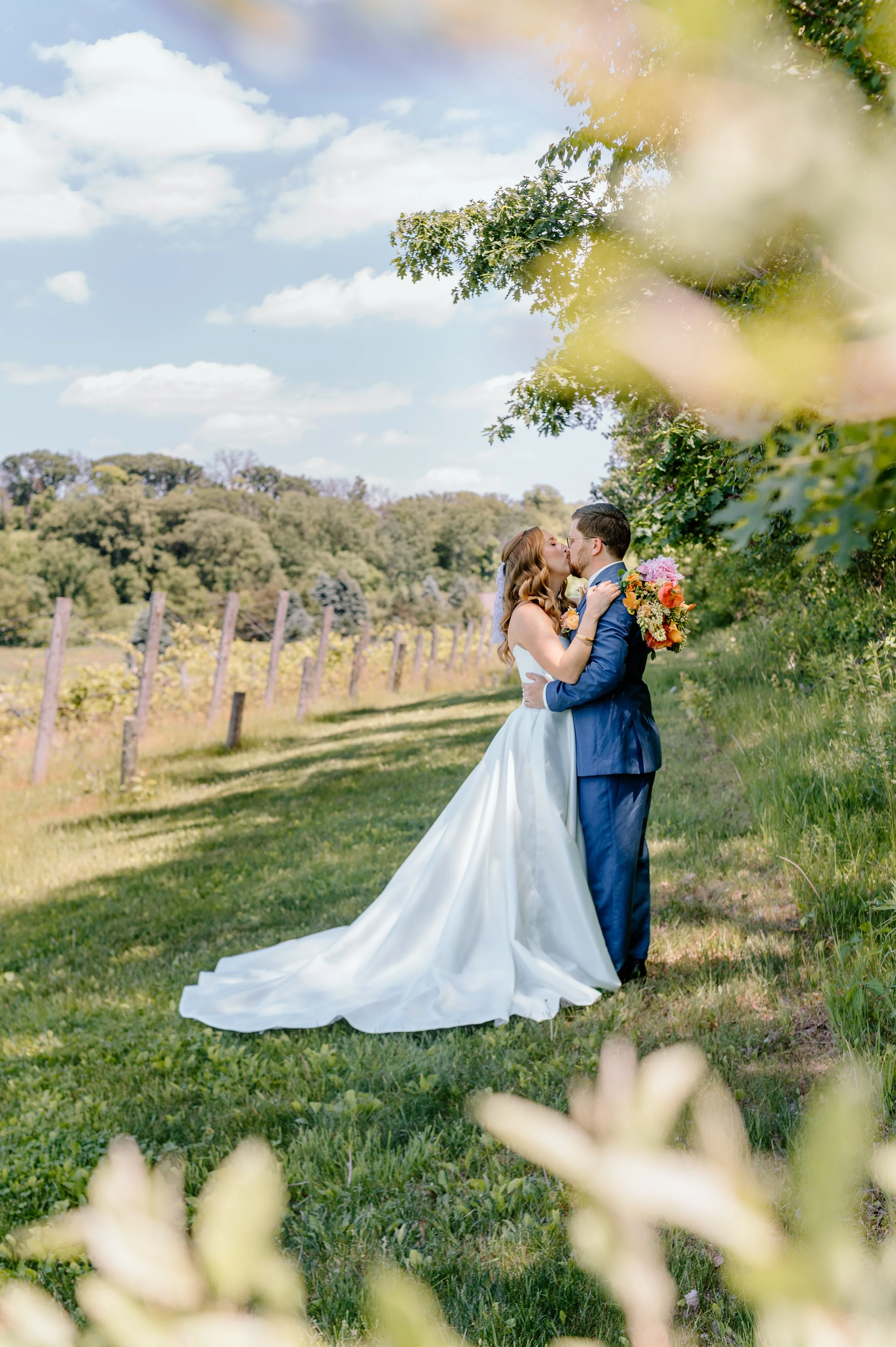 Bride and groom kiss in front of the grape vines at Belle Ame Vineyard wedding venue in River Falls, WI