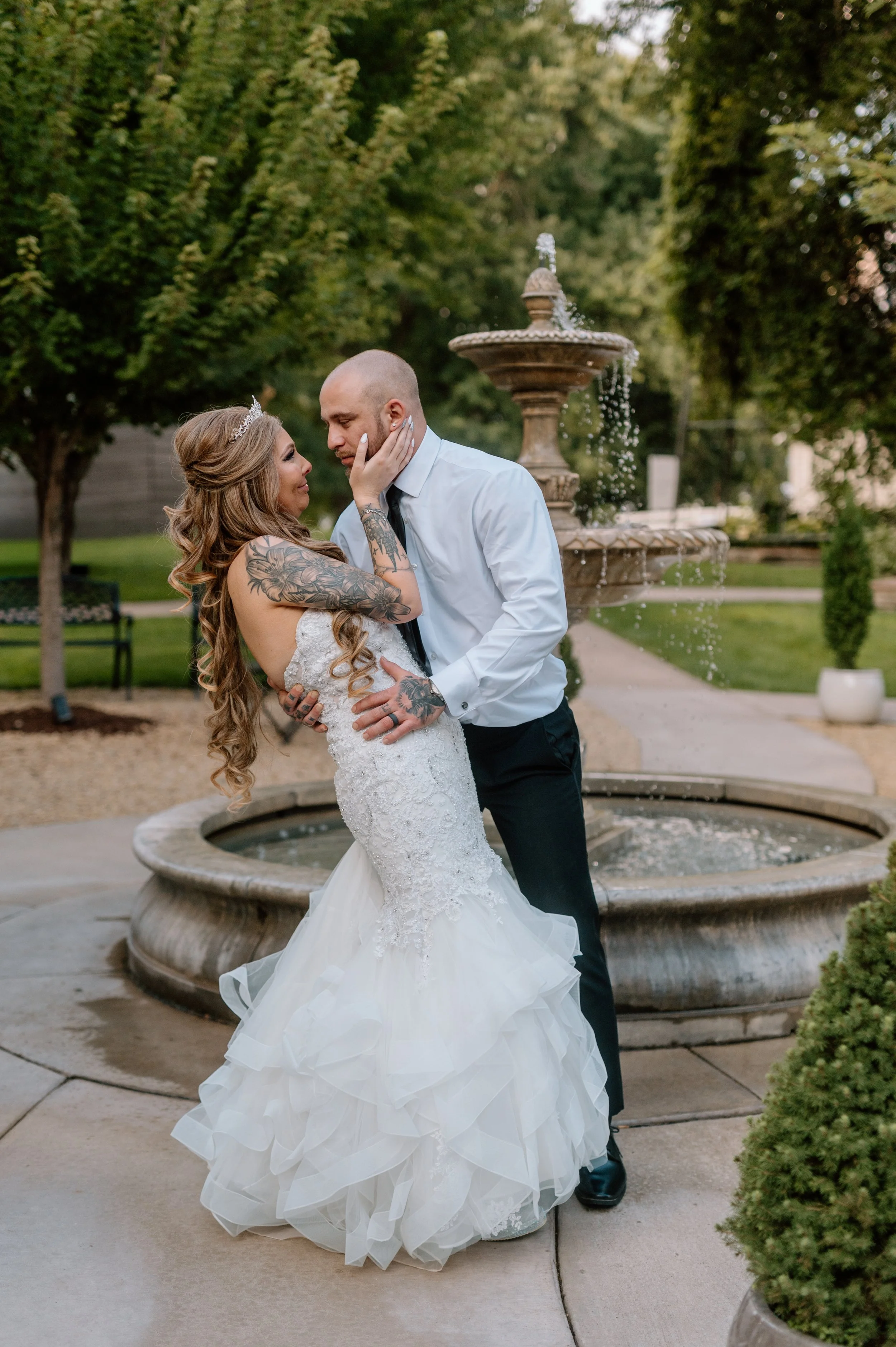 Groom starts to dip bride as they embrace in front of the fountain water feature at Legacy Hill Farm in Welch, MN