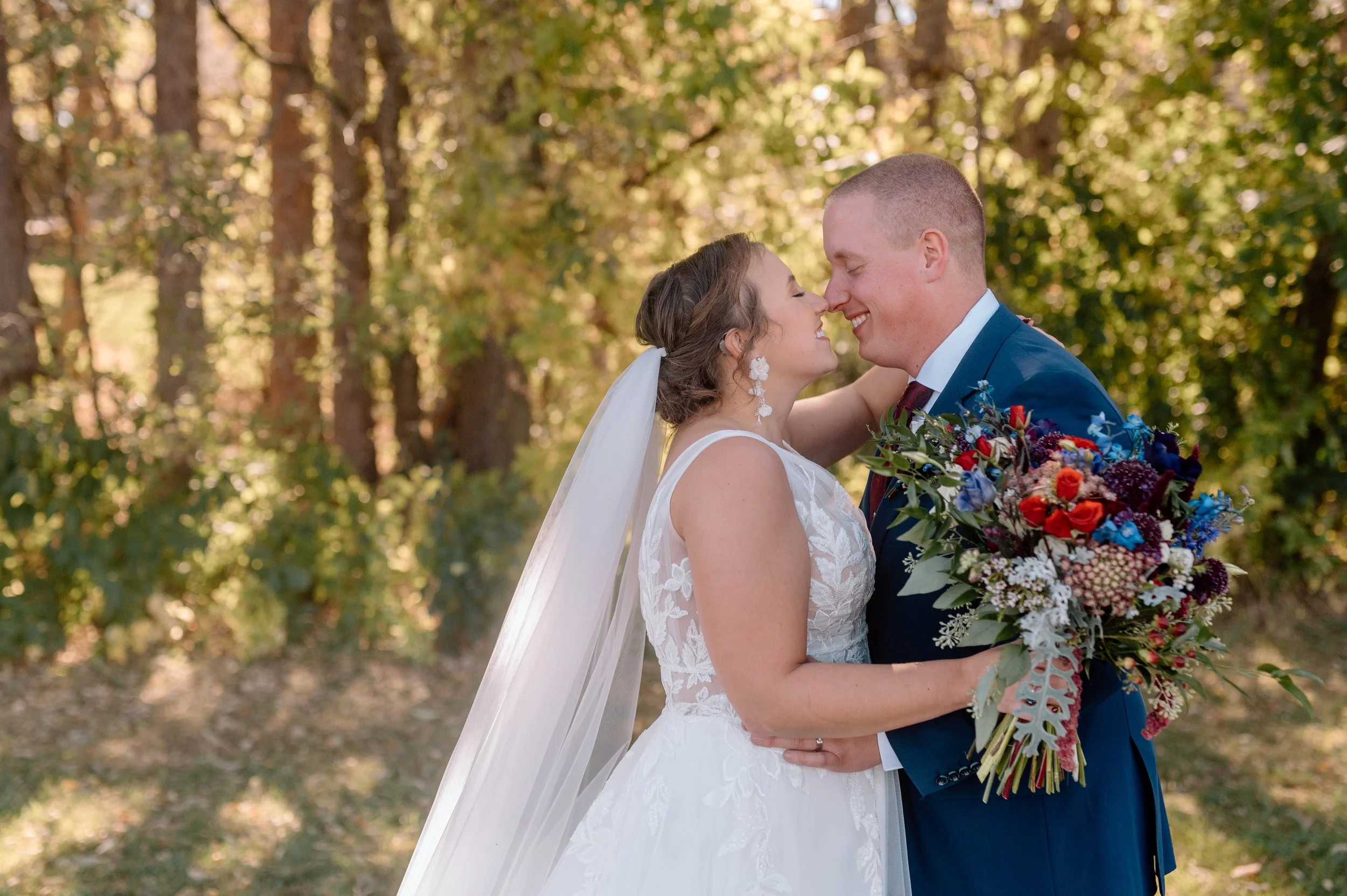 Bride and groom hold flowers and snuggle together on their wedding day at Stone Lion Winery and Events in Isanti, MN